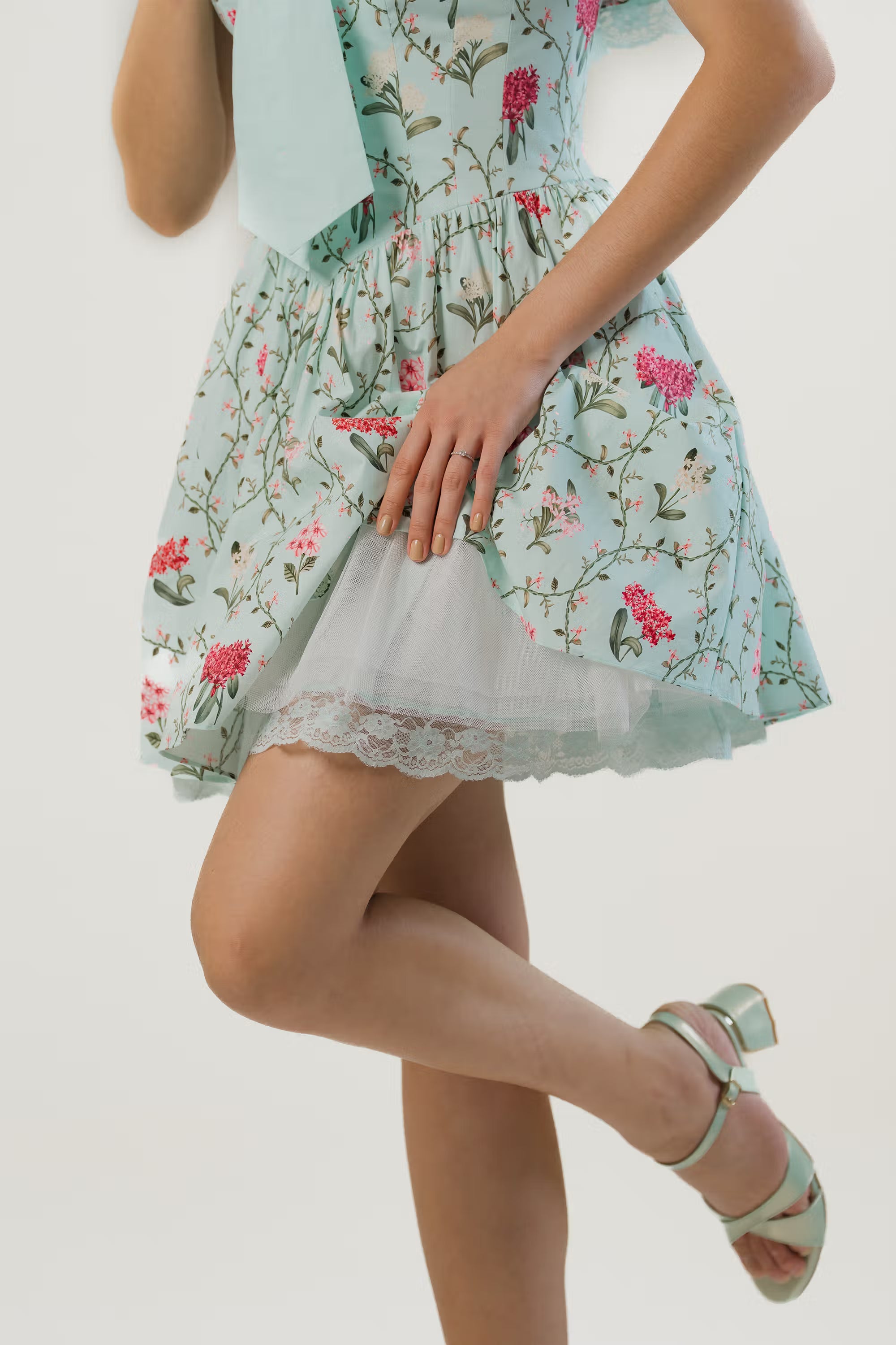 Detailed view of lace hem and layered skirt on mint green floral off-shoulder mini dress.