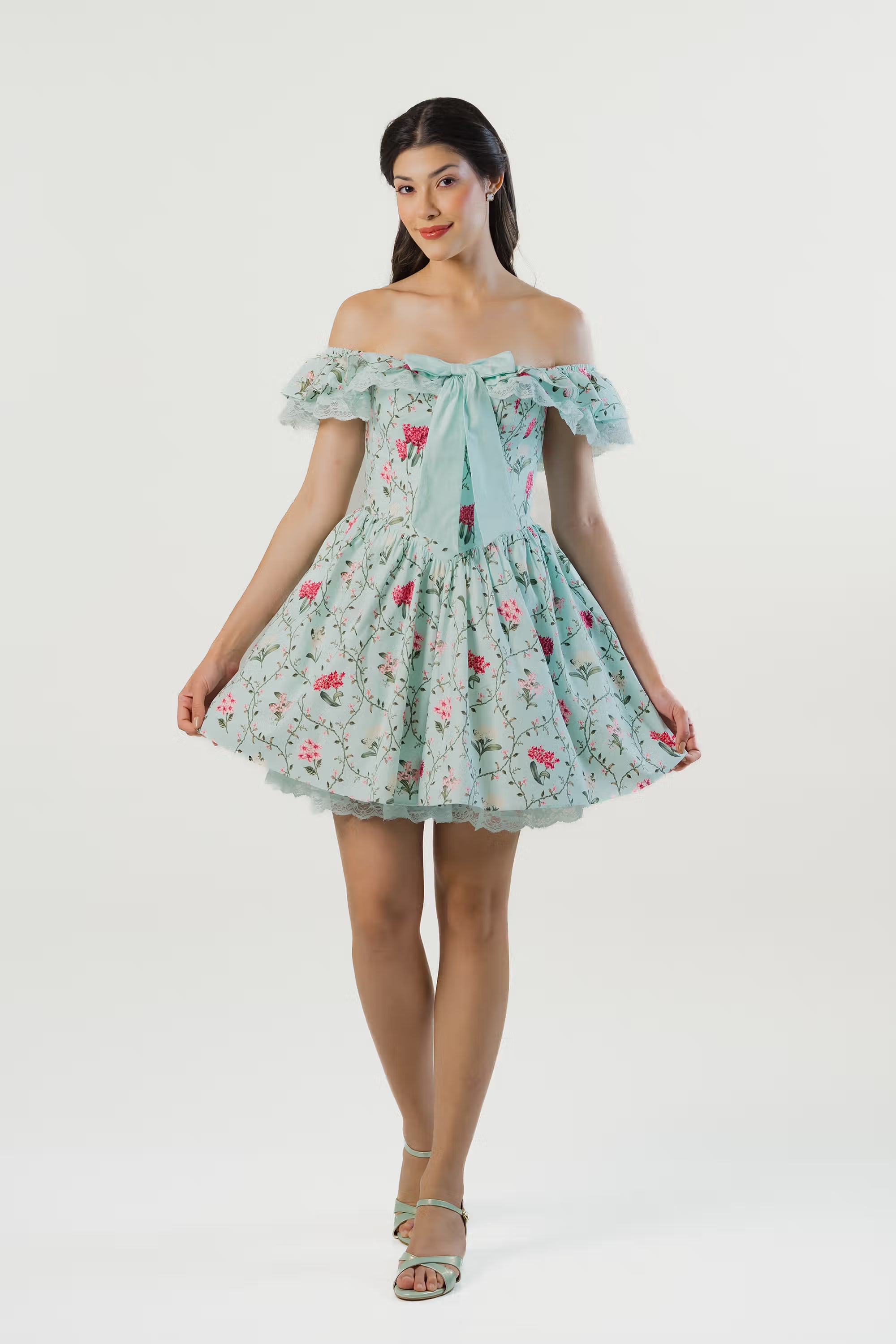 Women walking in mint green floral off-shoulder mini dress with bow tie front and lace details.