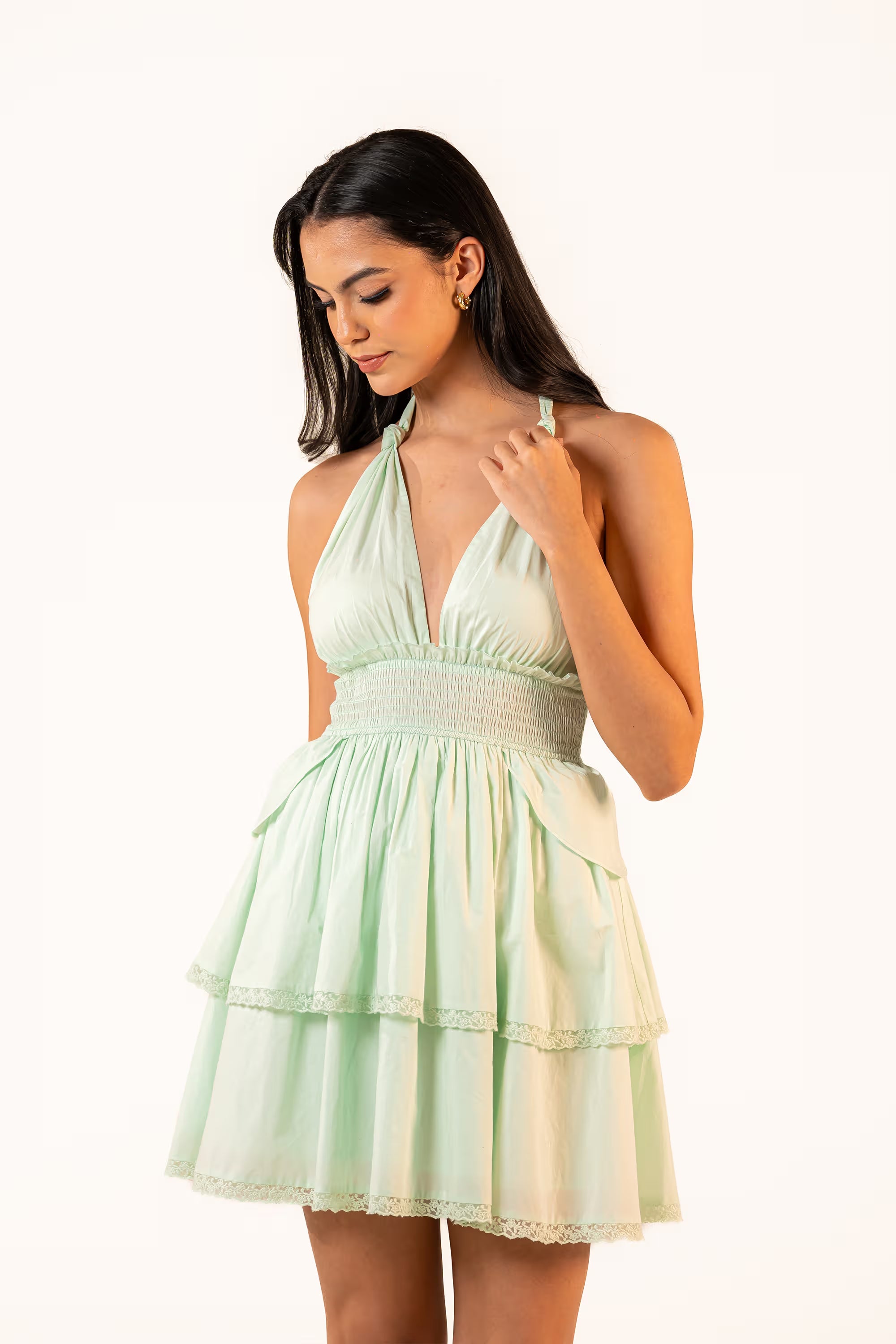 Close-up of mint green halter mini dress with ruched bust and smocked waist, feminine lace detail.