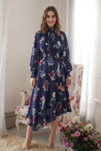 Woman in navy floral ruffle high-low midi dress with roses long sleeves and collared neckline