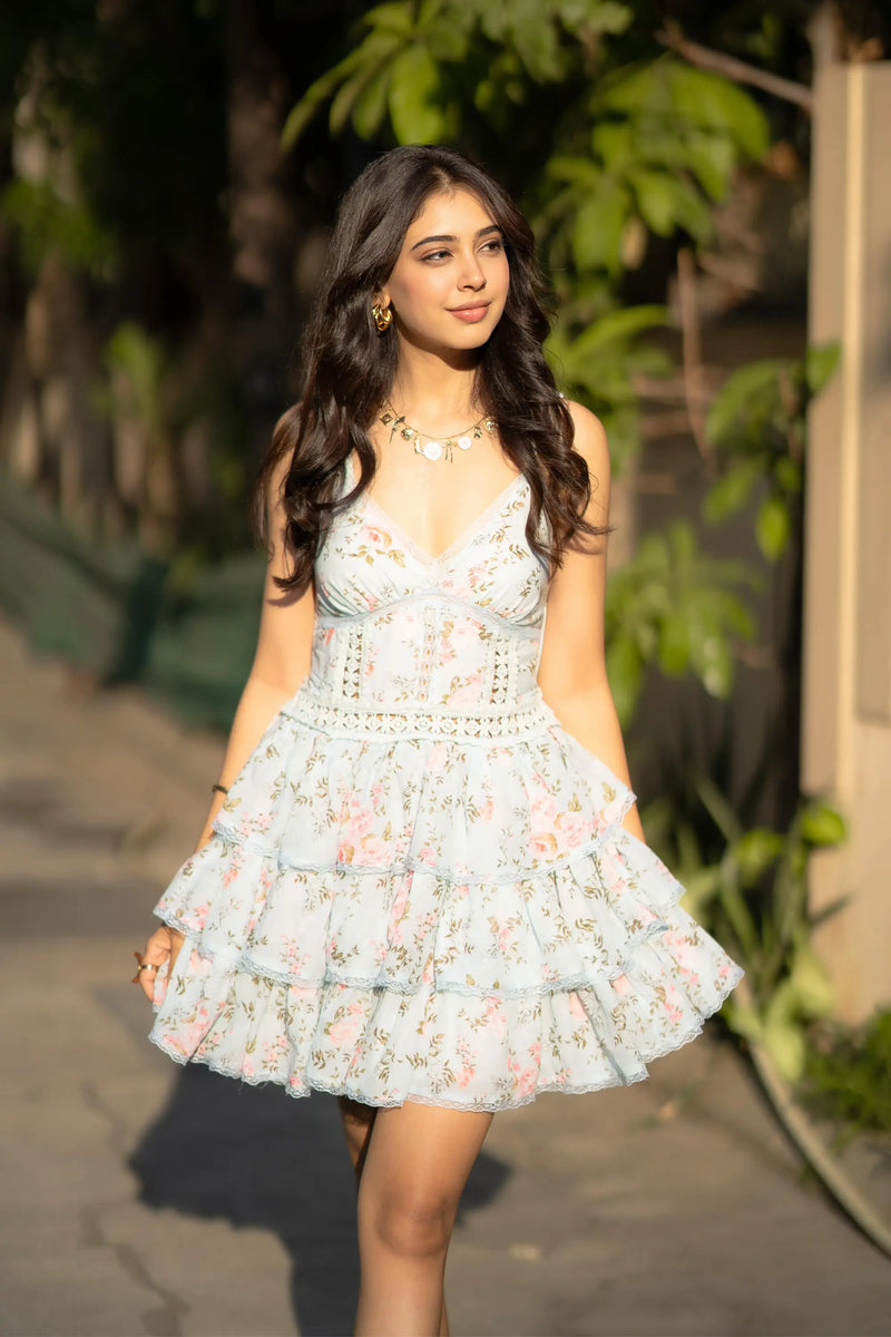 Niti Taylor wearing pastel blue floral ruffle mini dress with tiered skirt walking outdoors in soft evening light, summer street style India.