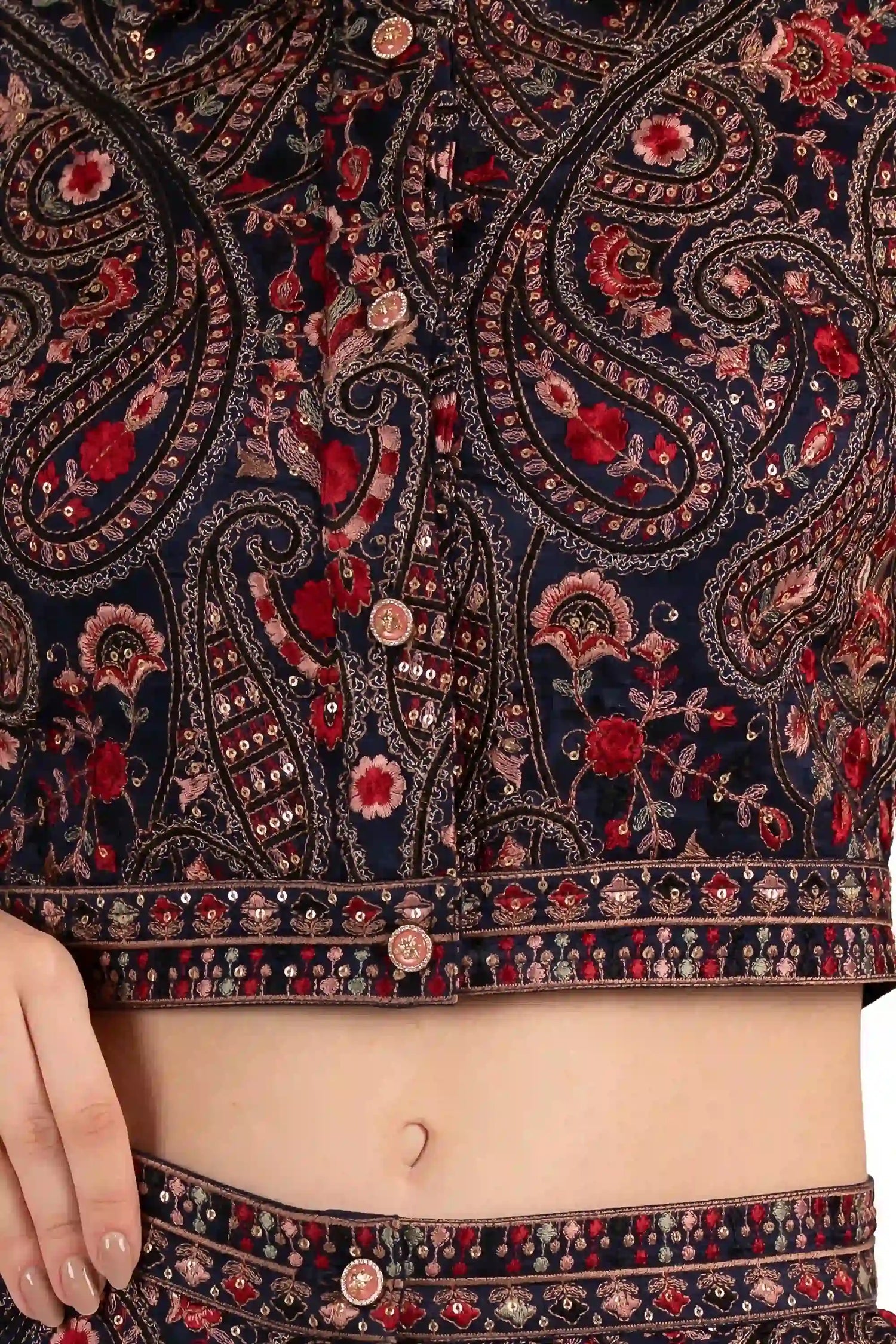Close-up detail of embroidered buttons and paisley pattern on women's crop top, traditional Indian ethnic style