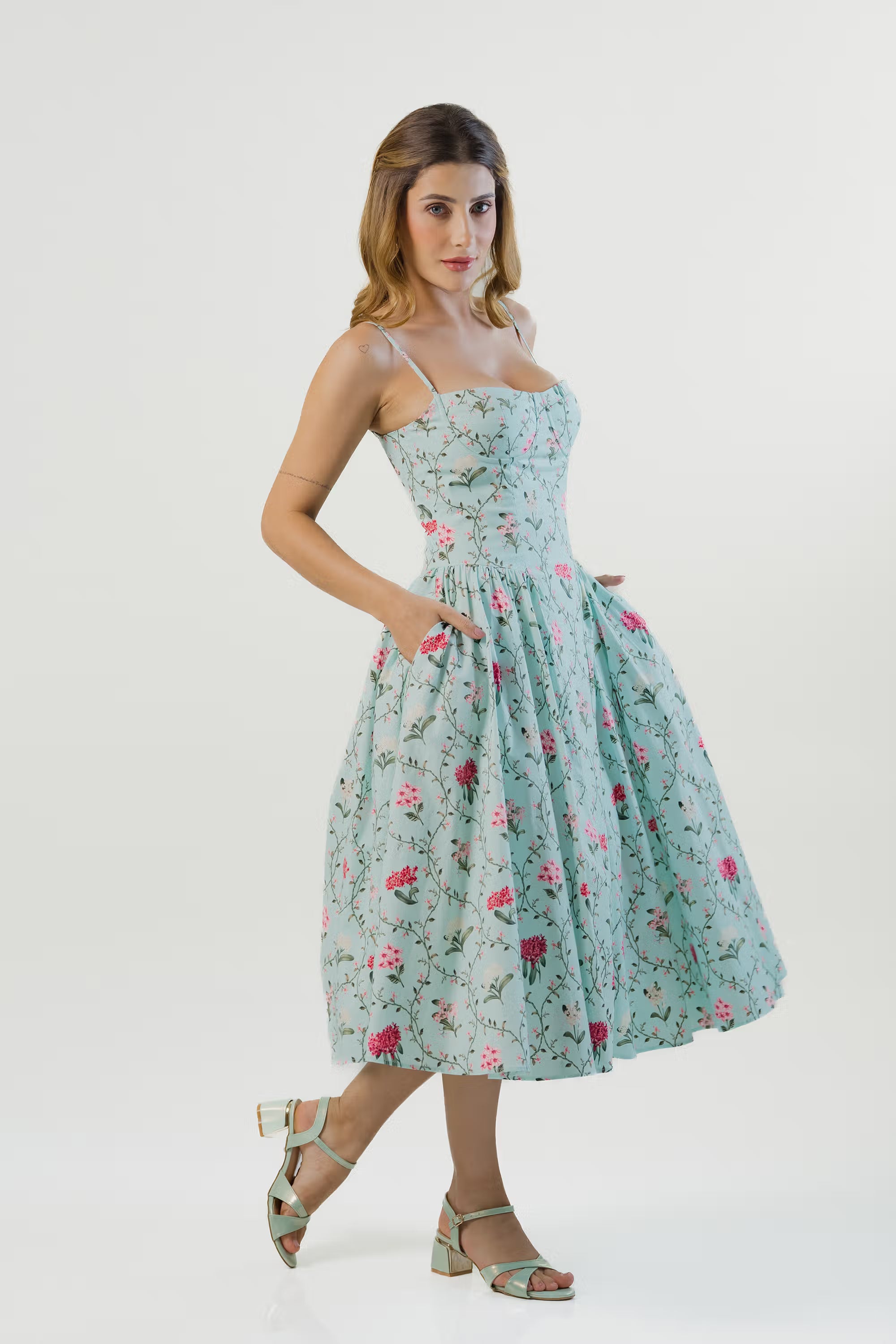Pastel green floral midi dress, side view, pockets and block heels.