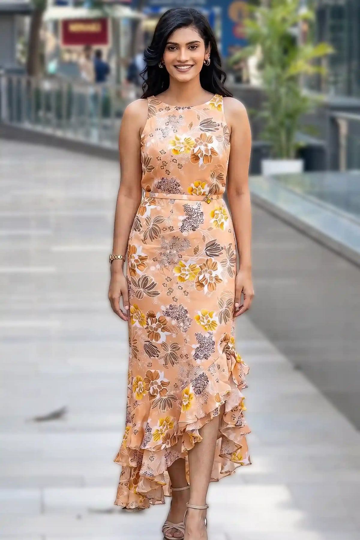 Woman in peach floral high-low maxi dress with sleeveless halter neckline and ruffle hem