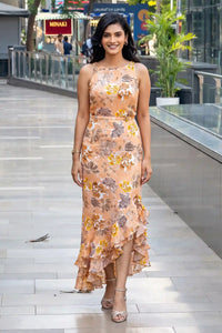 Woman in peach floral high-low maxi dress with sleeveless halter neckline and ruffle hem
