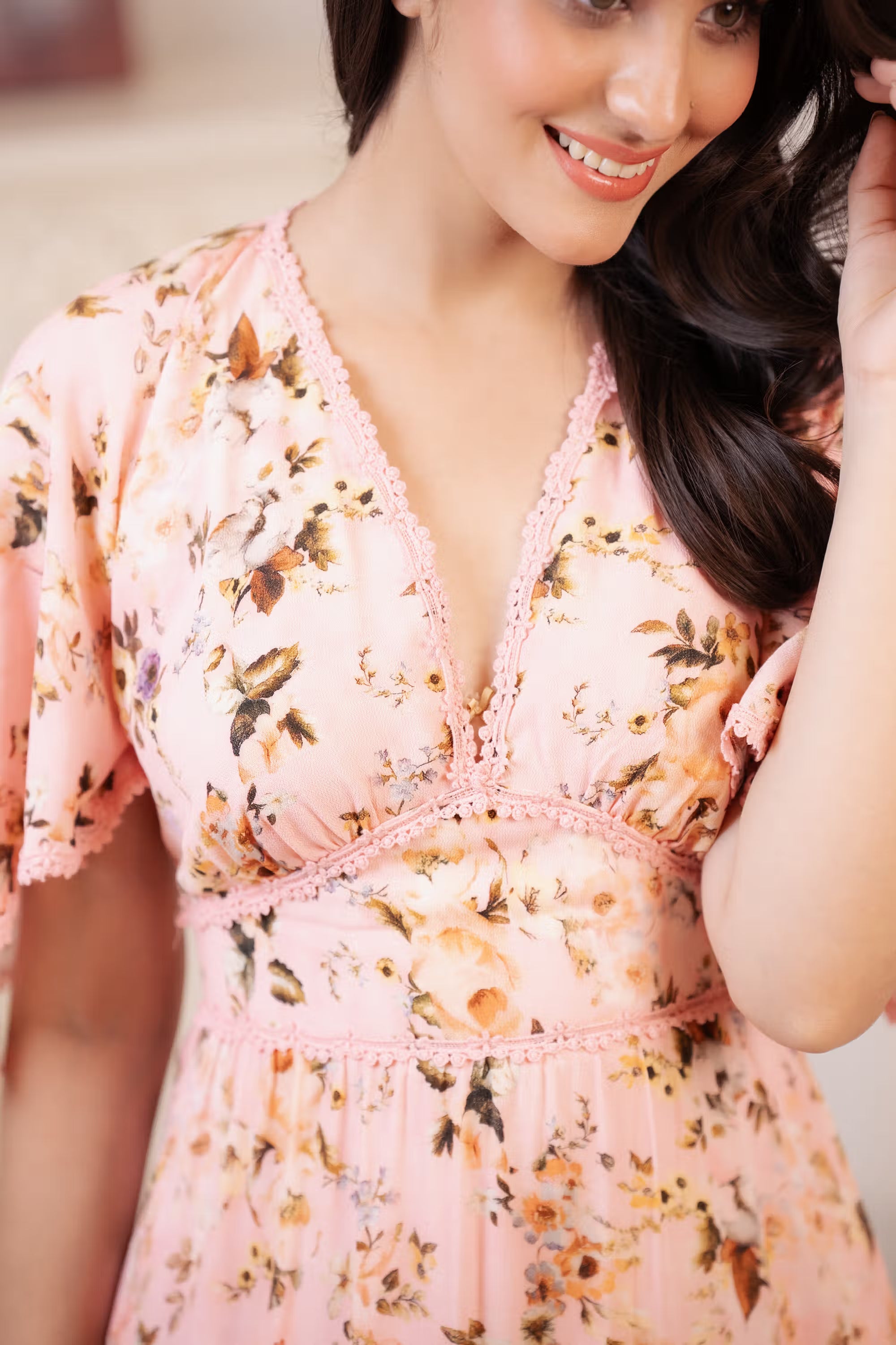 Neckline detail of peach pink floral maxi dress with lace trim and V-cut design