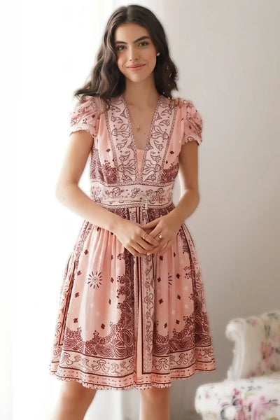 Woman in pink bandana belted v-neck mini dress with puffed sleeves ornate border print vintage