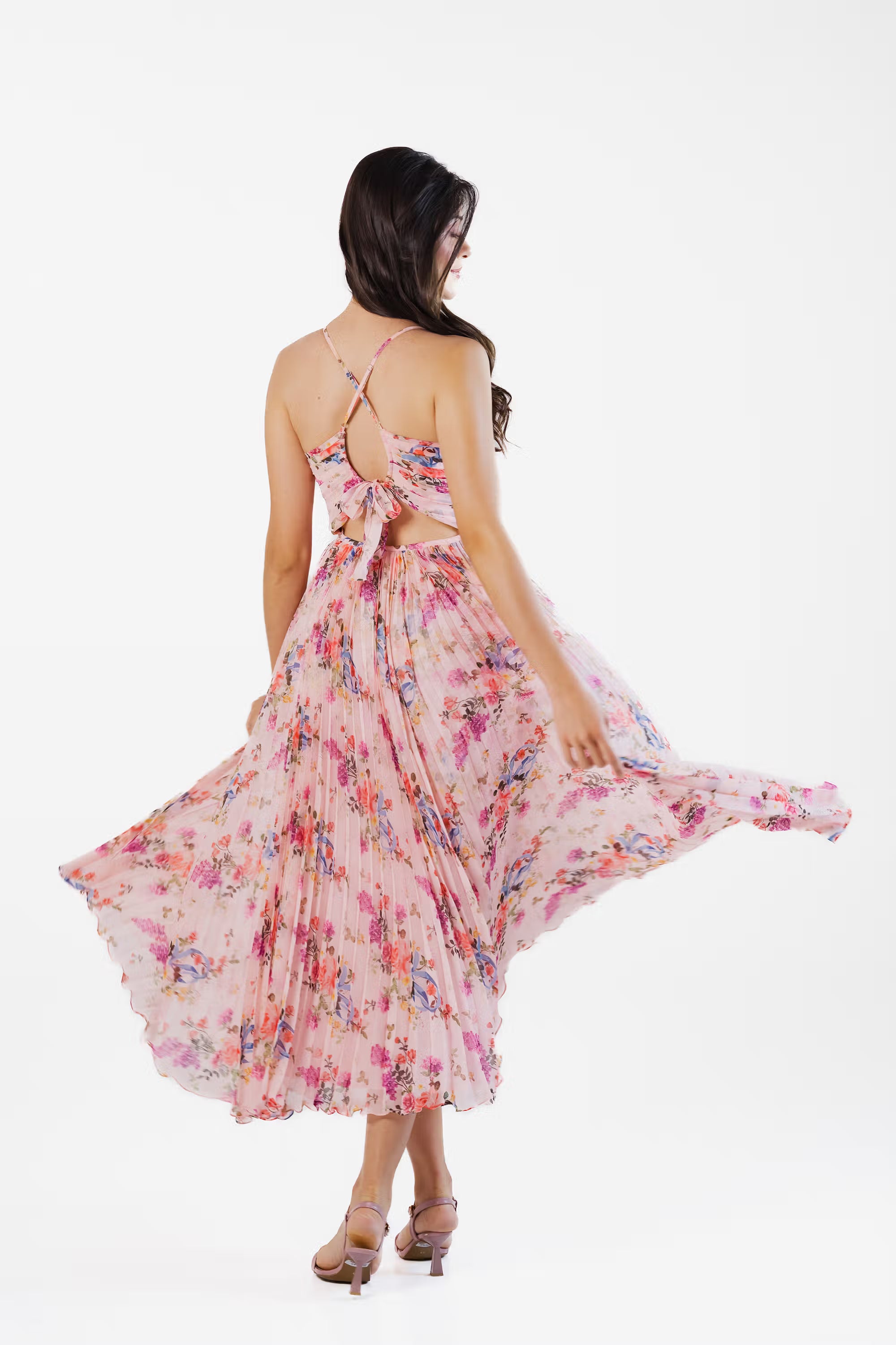 Back view of pink floral pleated maxi dress with bow tie closure and cutout detail.