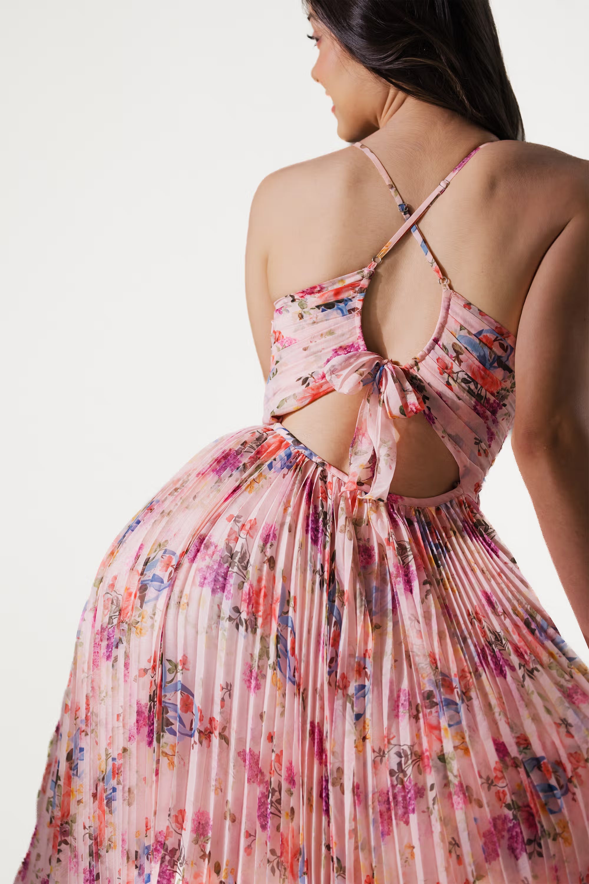 Close-up backless detail of pink floral maxi dress with criss-cross straps and bow tie.