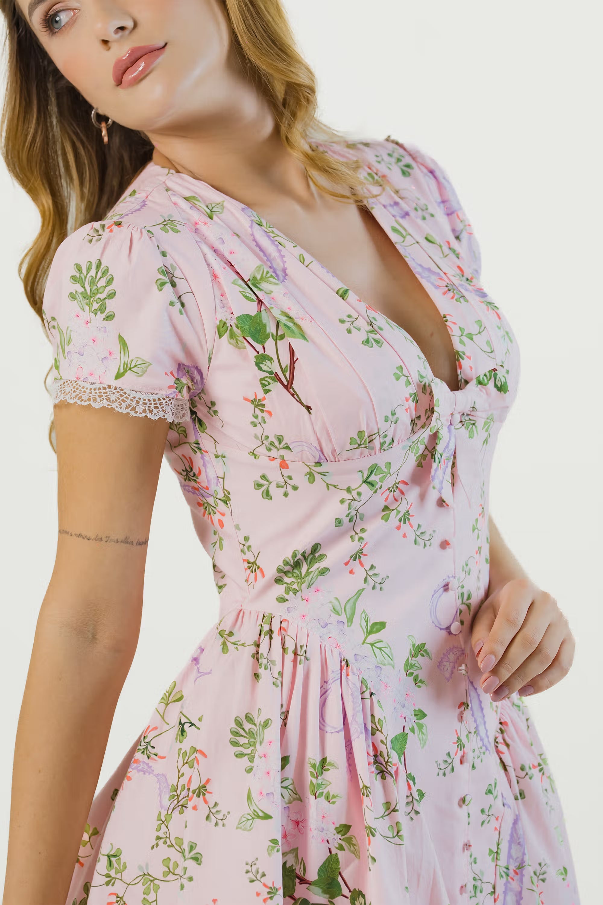 Close-up of pink floral dress showing v-neckline, puff sleeves, lace trim and fitted waist detail.