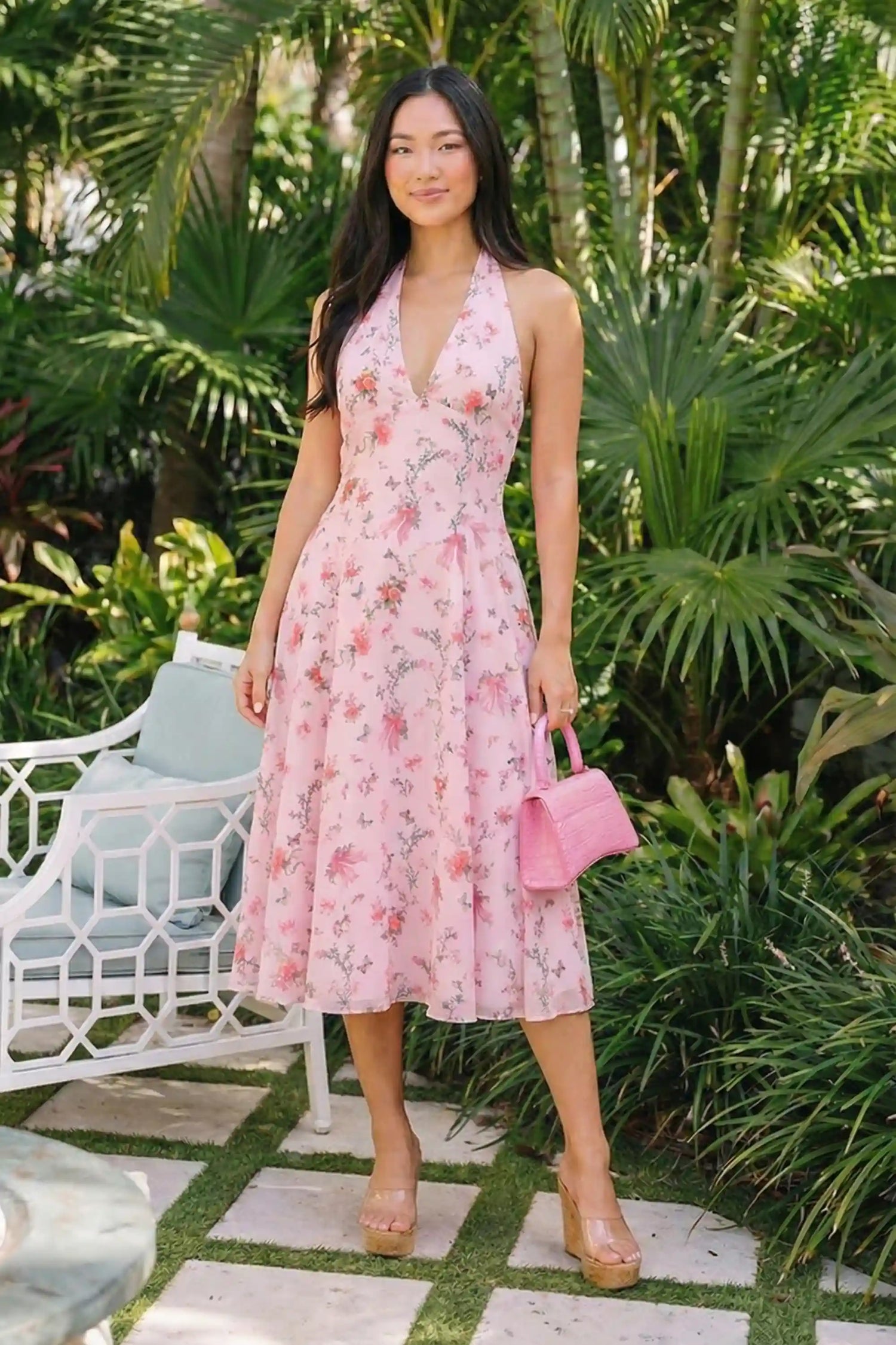 Pretty Pixie pink floral bow print halter v-neck midi dress front view tropical setting