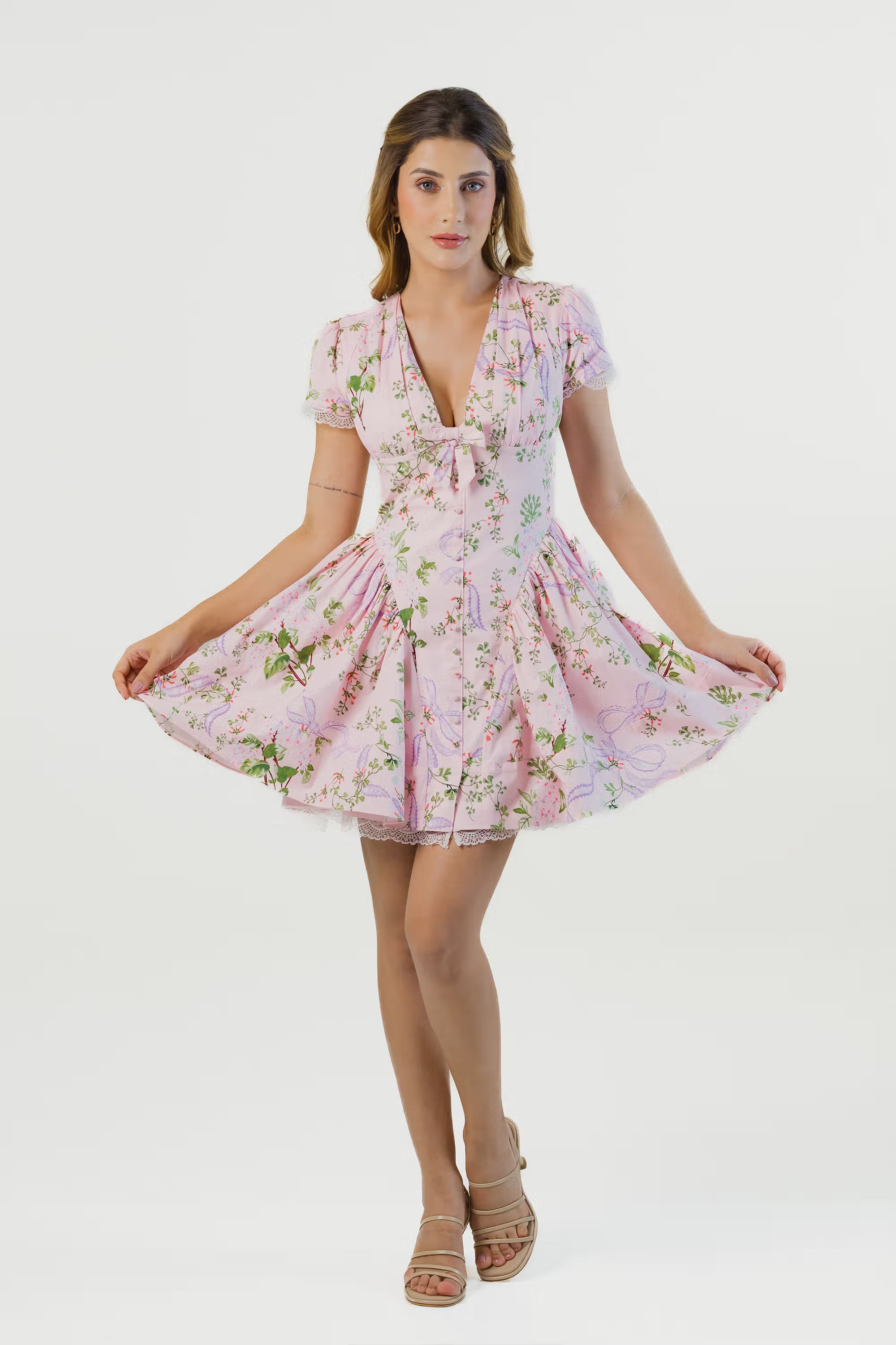 Women showing flared skirt of pink floral mini dress with lace hem, puff sleeves and fitted waist.
