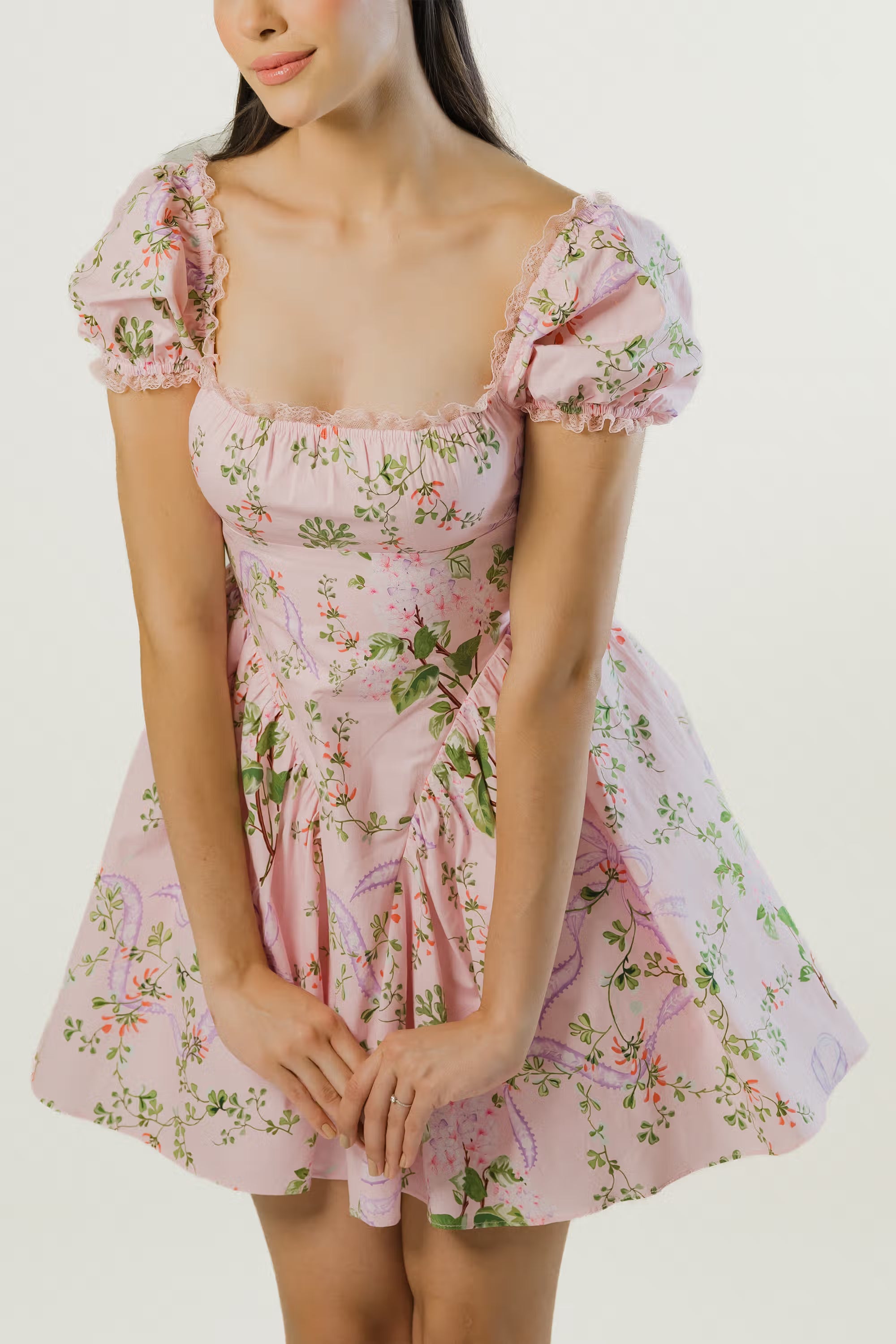 Detail of square neckline and bodice design on pink puff sleeve floral dress with lace trim.