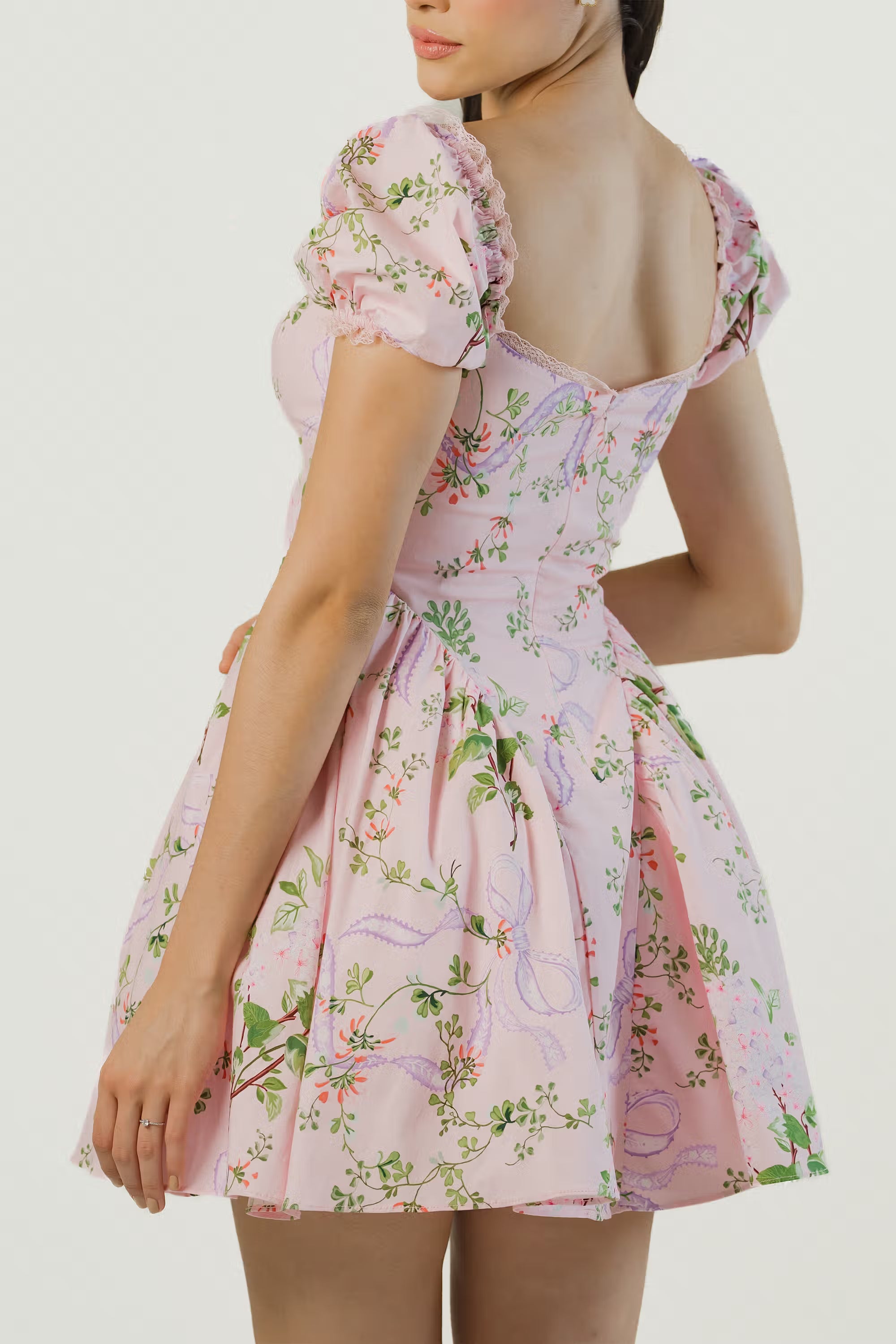 Over-the-shoulder back pose showcasing pink floral puff sleeve dress with flattering fit.