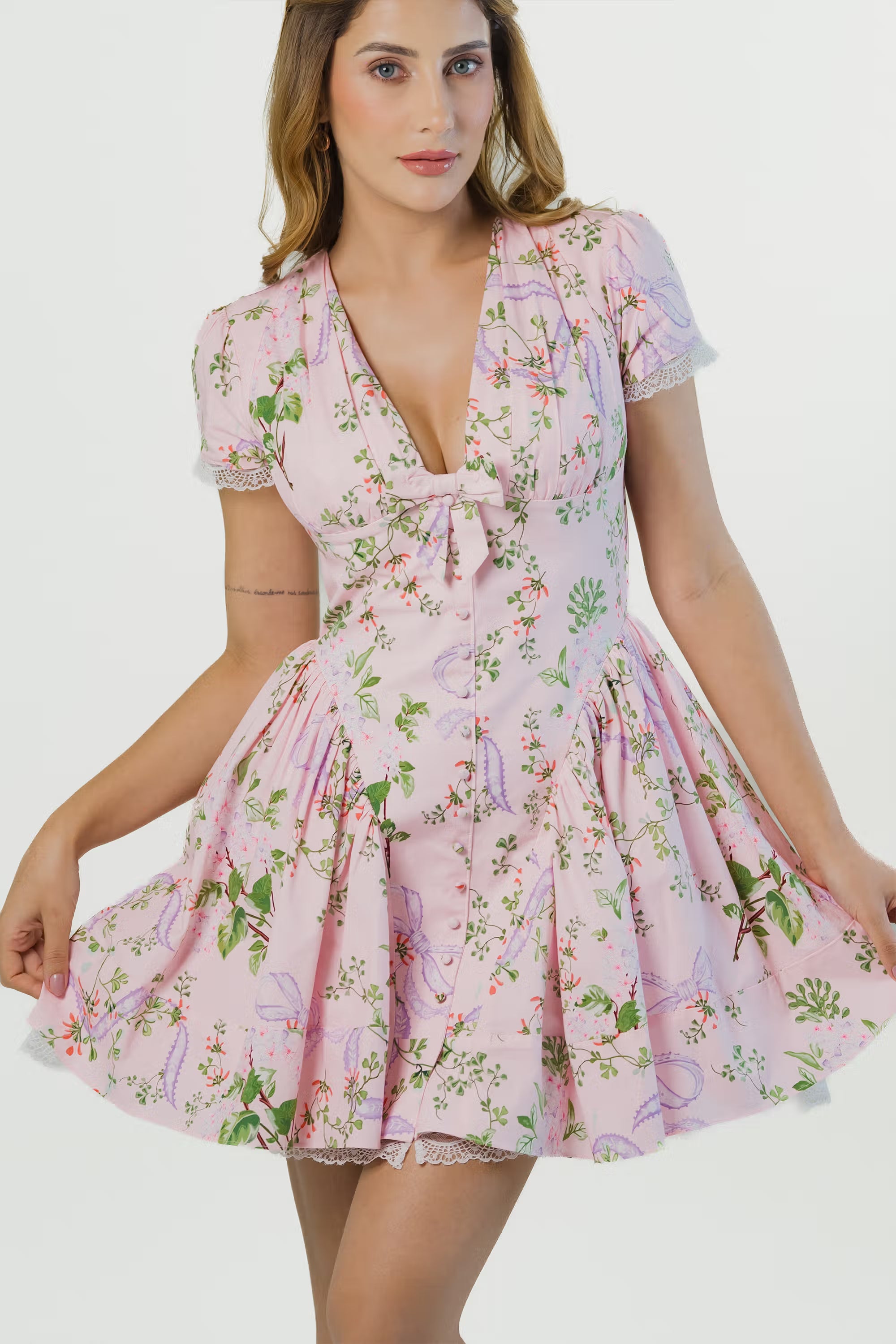 Front pose of pink floral short dress with flare skirt, v-neckline, puff sleeves and lace edge.
