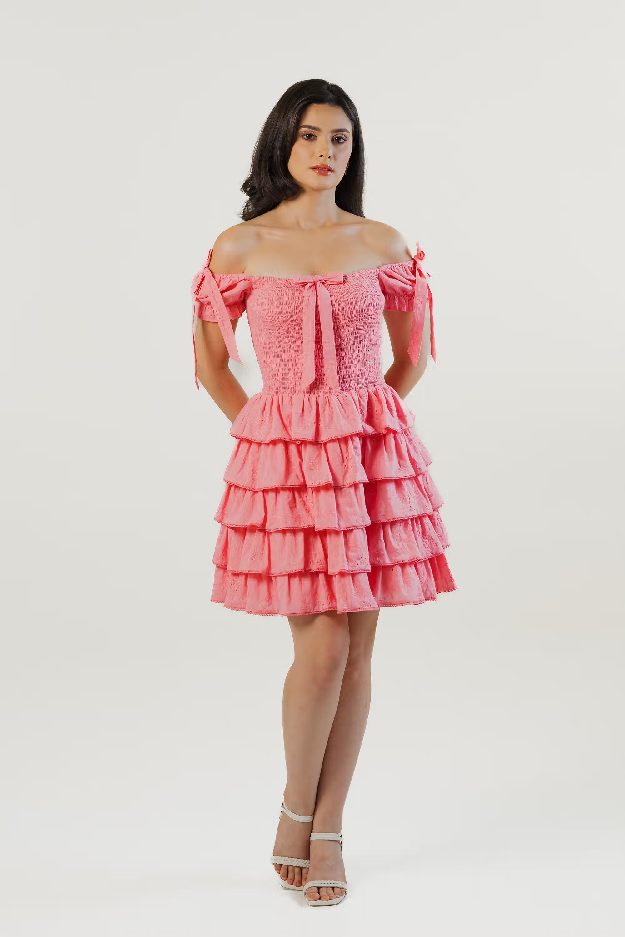 Women wearing pink off-shoulder ruffle mini dress with bow tie sleeves and smocked bodice, front view
