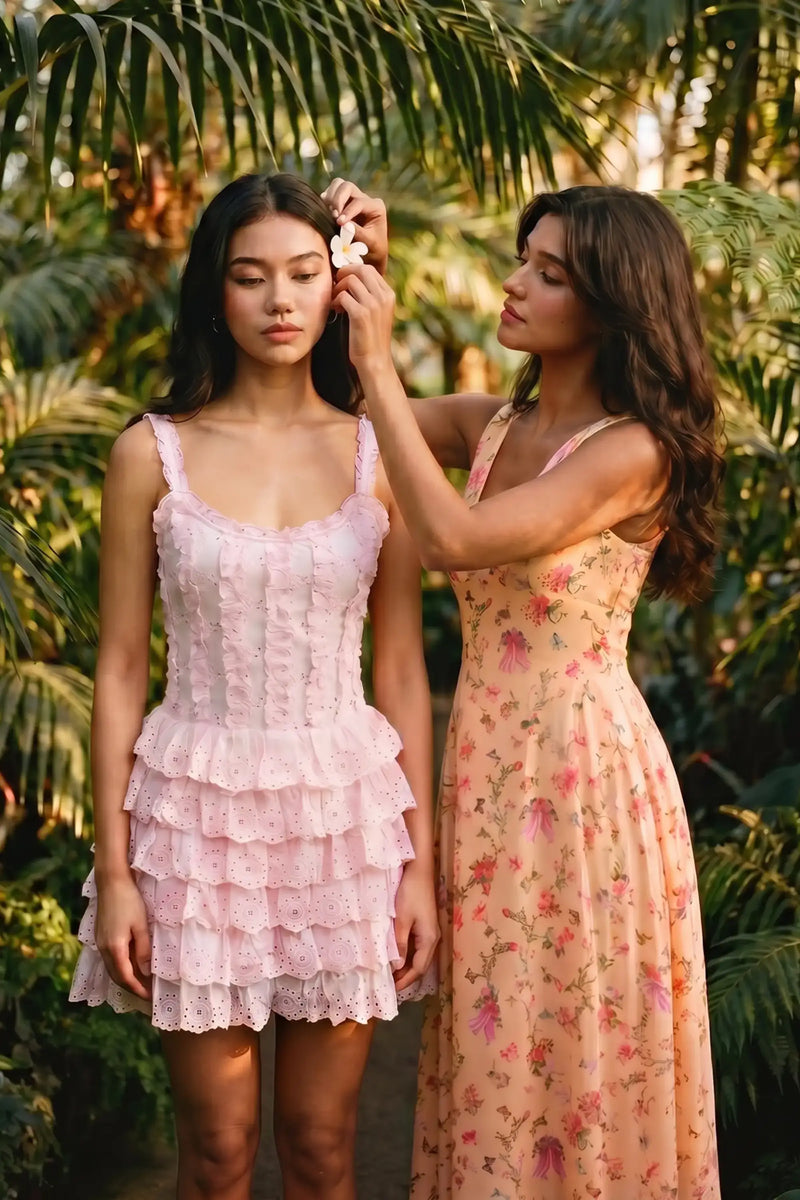 Women in pink ruffled sleeveless dress and peach floral midi dress under palm trees; organic cotton resort wear and tropical vacation dresses