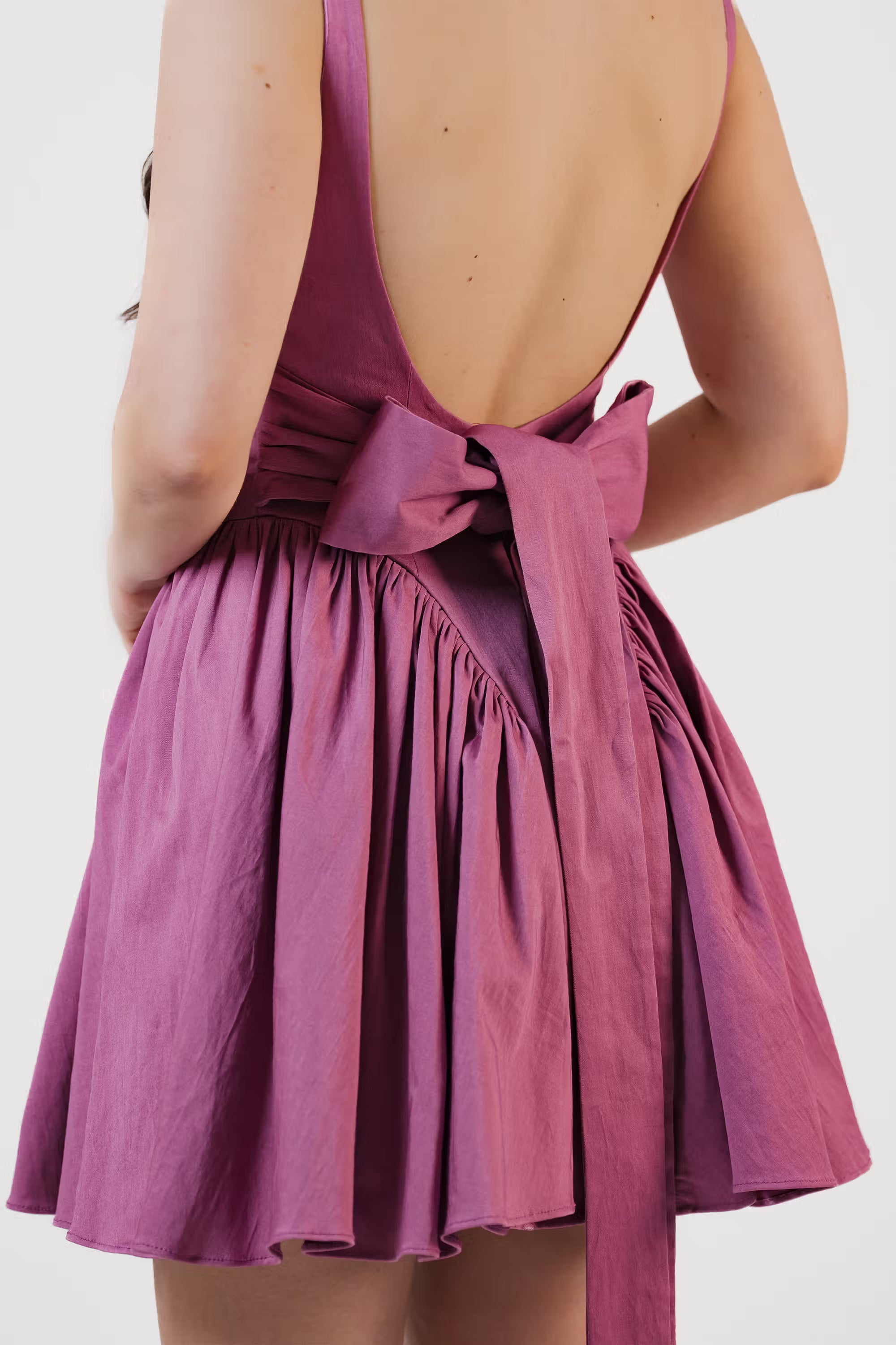 Detailed shot of plum purple mini dress back bow with ruched skirt design