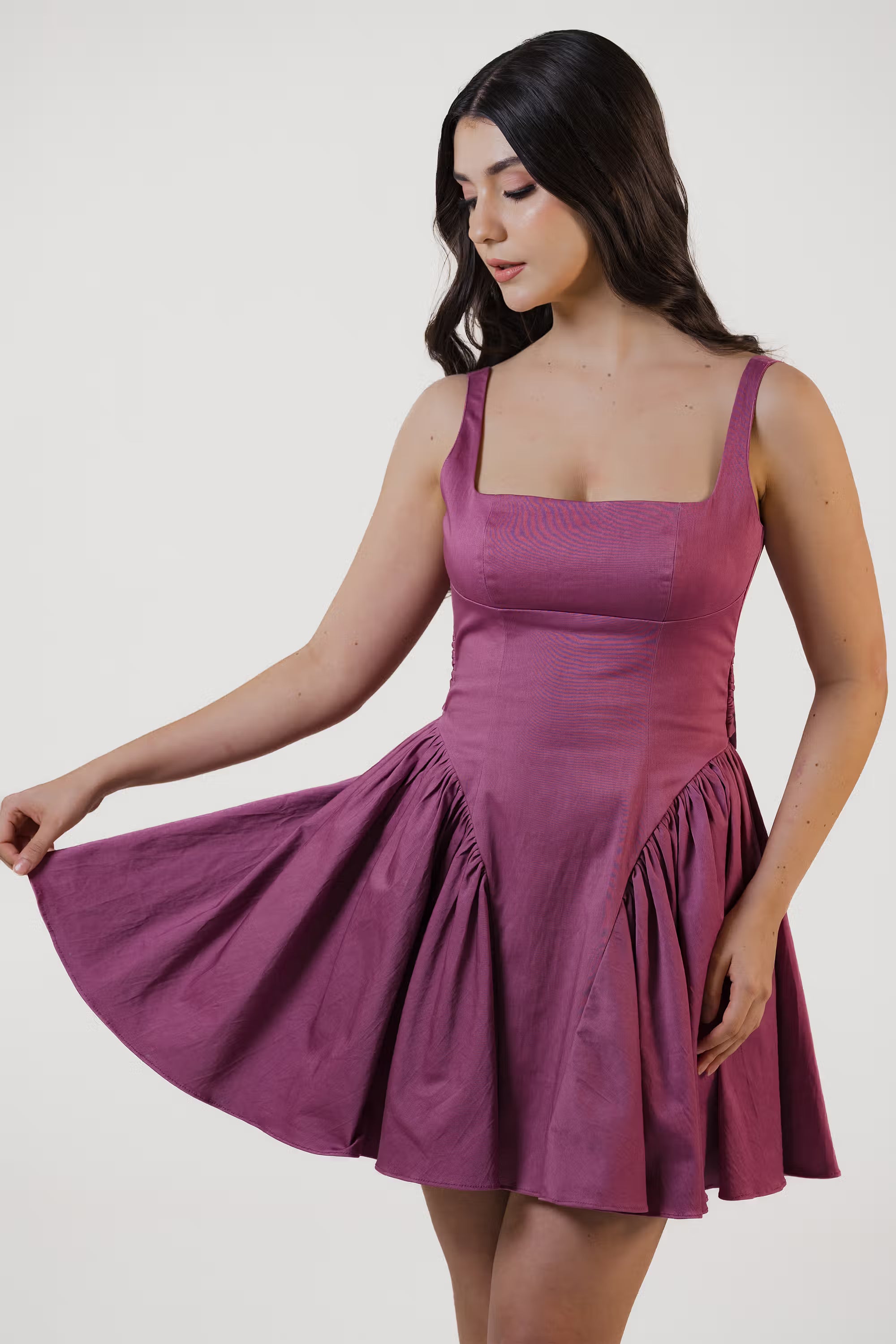 Close-up of plum purple mini dress with ruched skirt detail and structured bodice