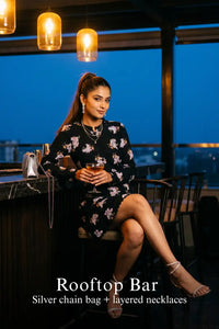 Woman in Pretty Pixie midnight iris floral belted long-sleeve mini dress styled for a rooftop bar