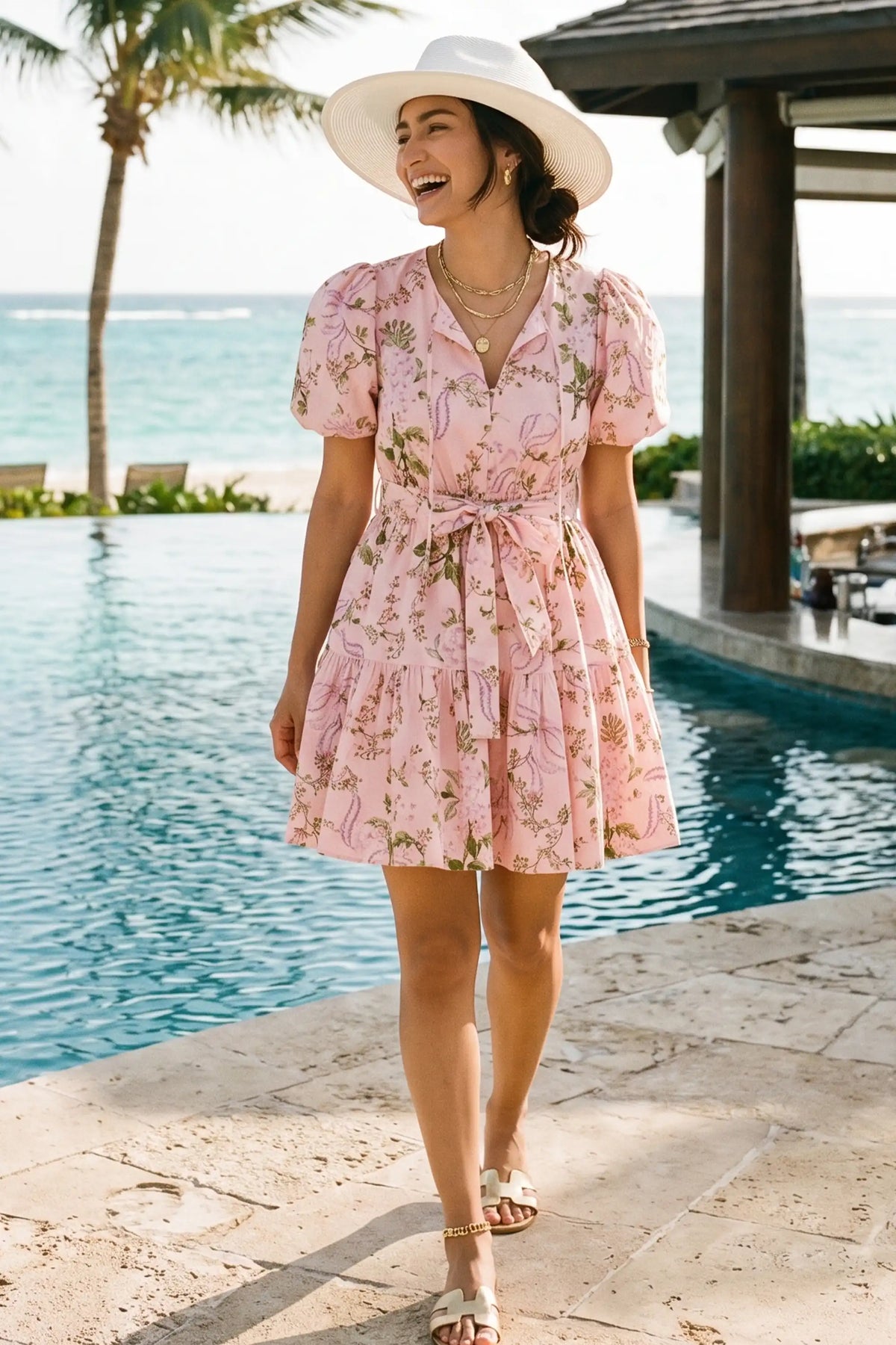 Woman laughing poolside at a resort wearing Pretty Pixie's blossom pink puff-sleeve bow-belted mini dress