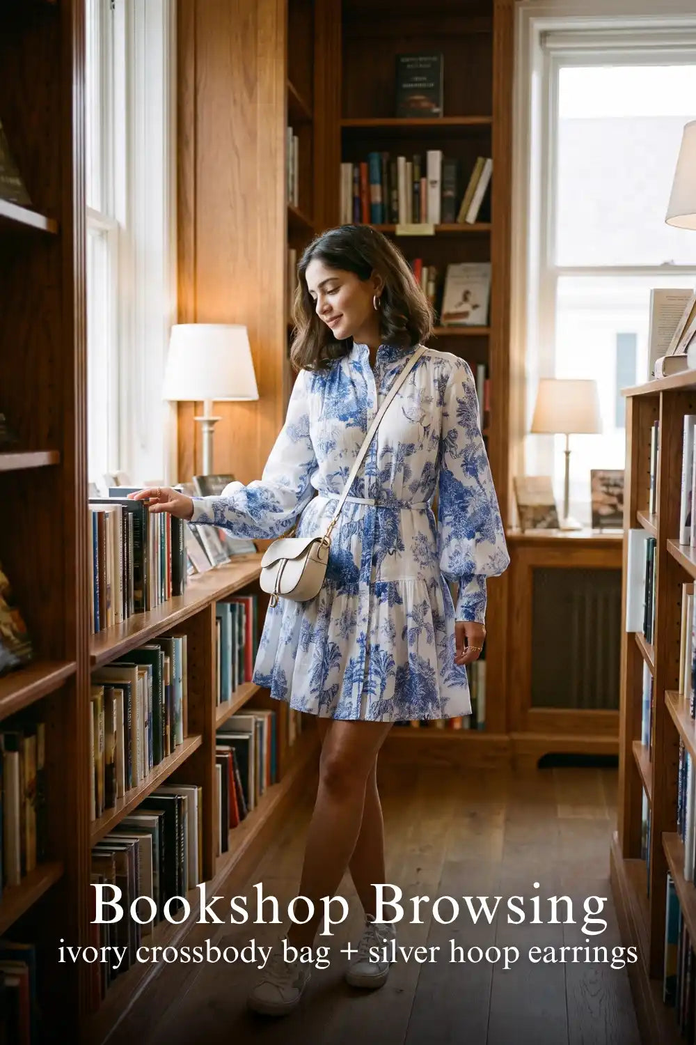 Woman in Pretty Pixie indigo toile button-front belted tiered mini dress styled for a bookshop browsing