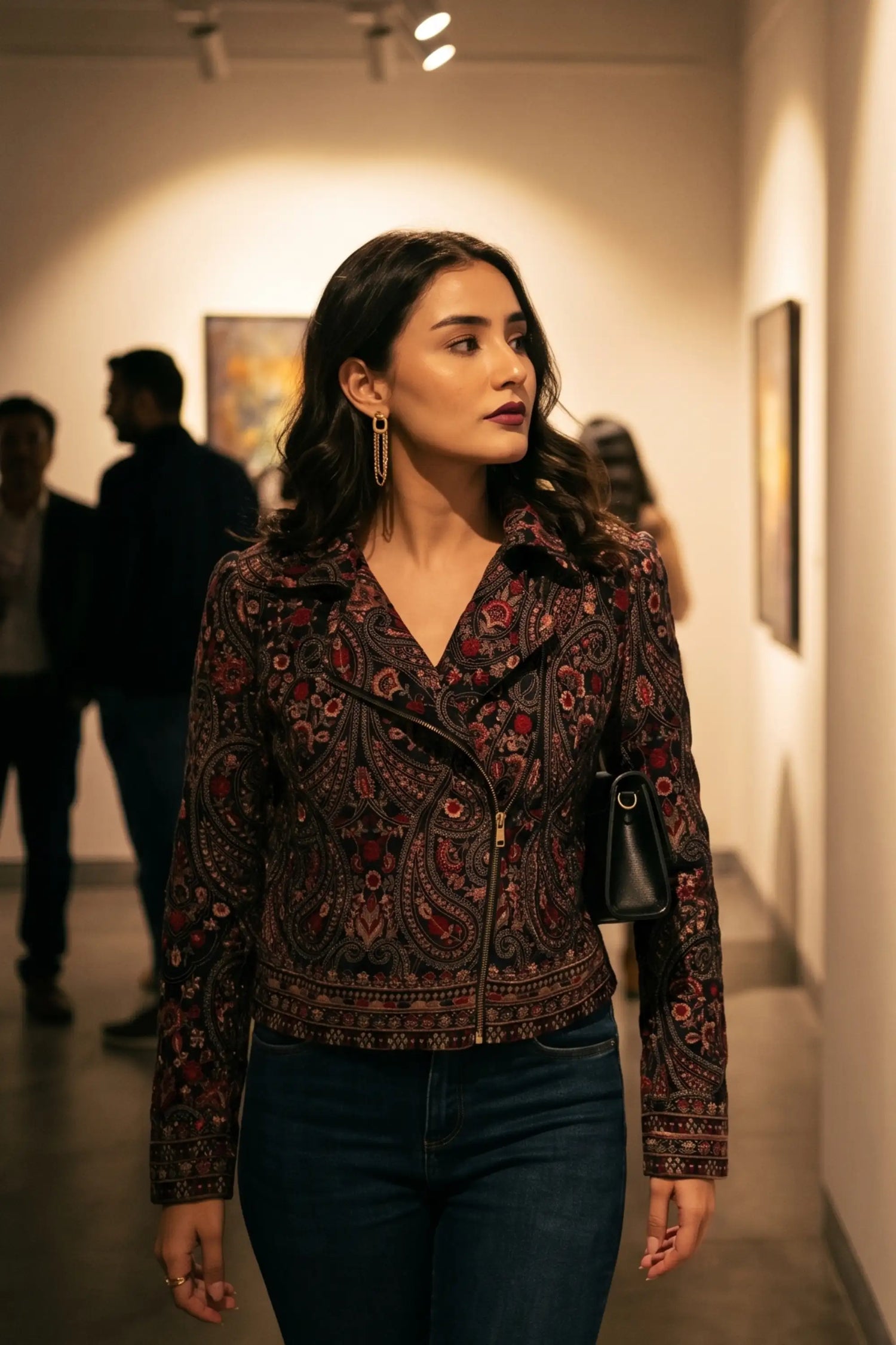 Woman in crimson paisley navy hand embroidered biker jacket with statement drop earrings at art gallery opening - Pretty Pixie eveningwear