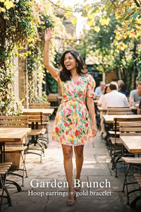 Woman in Pretty Pixie tropical floral puff-sleeve wrap mini dress styled for a garden brunch 2