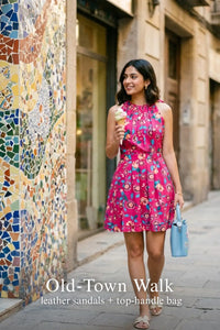 Woman in Pretty Pixie raspberry sorbet floral sleeveless belted mini dress styled for an old town walk