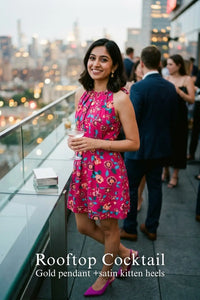 Woman in Pretty Pixie raspberry sorbet floral sleeveless belted mini dress styled for a rooftop cocktail
