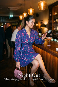 Woman in Pretty Pixie royal indigo floral v-neck puff-sleeve belted mini dress styled for a night out