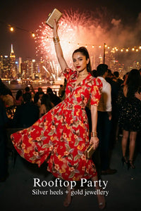 Woman in Pretty Pixie red botanical v-neck belted shirt midi dress styled for a rooftop party