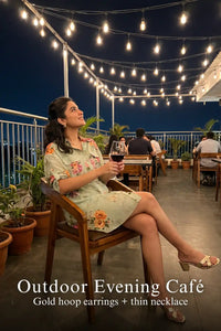 Woman in Pretty Pixie sage floral belted shirt mini dress styled for an outdoor evening cafe
