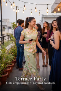 Woman in Pretty Pixie sage green floral co-ord top & wide pants styled for a terrace party