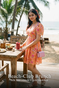 Woman in Pretty Pixie peach blossom floral v-neck flutter sleeve mini dress styled for a beach club brunch