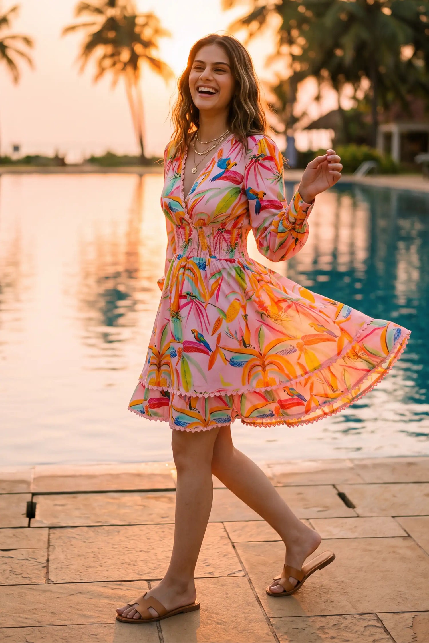 Woman twirling in vibrant floral ruffled V-neck mini dress with tropical parrot print at poolside during sunset - Pretty Pixie resort wear