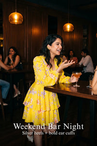 Woman in Pretty Pixie marigold tie-neck ruffle mini dress styled for a weekend bar night
