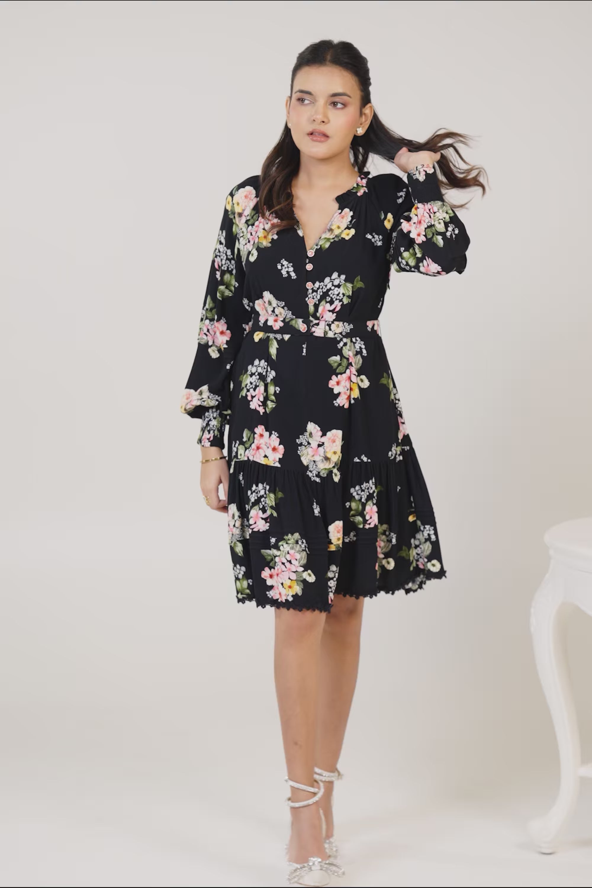 Black floral mini dress showing colorful floral pattern and waist belt.