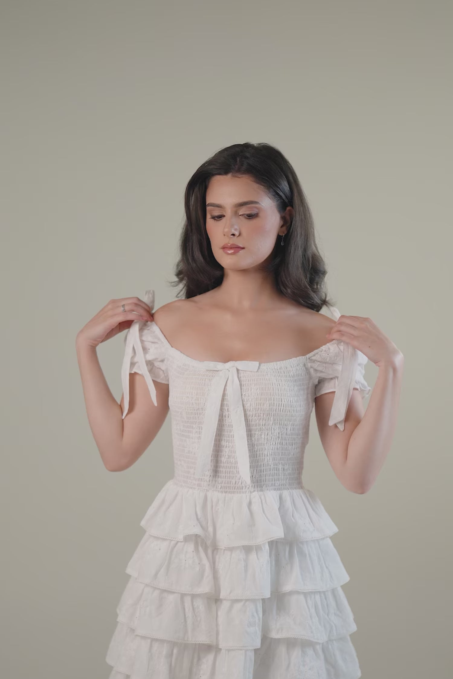 Woman wearing a white off-shoulder ruffle mini dress with tiered skirt,  summer party outfit.