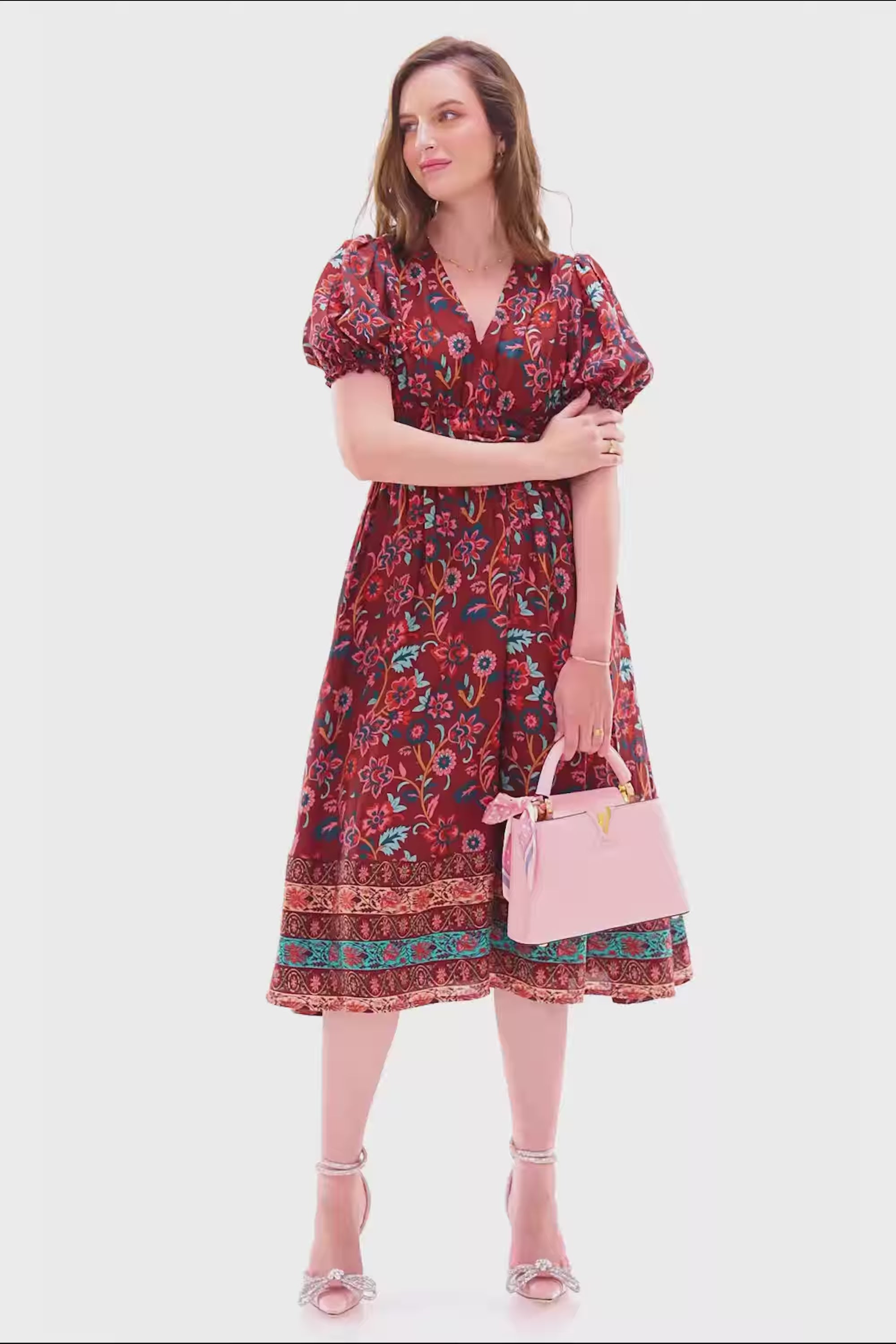 Woman in burgundy floral puff sleeve midi dress with shirred waist.
