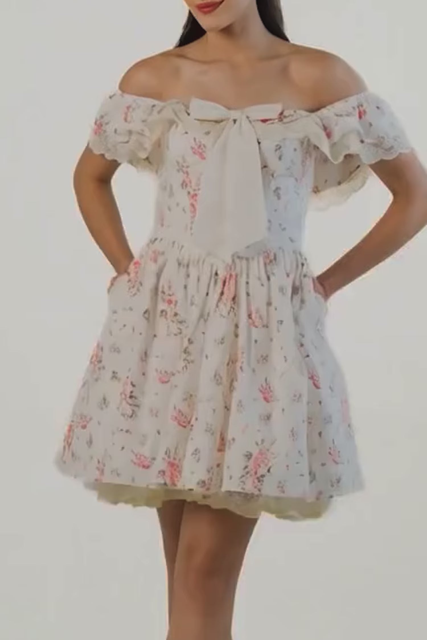 Cream floral off-shoulder mini dress with oversized bow at the chest and ruffled neckline.