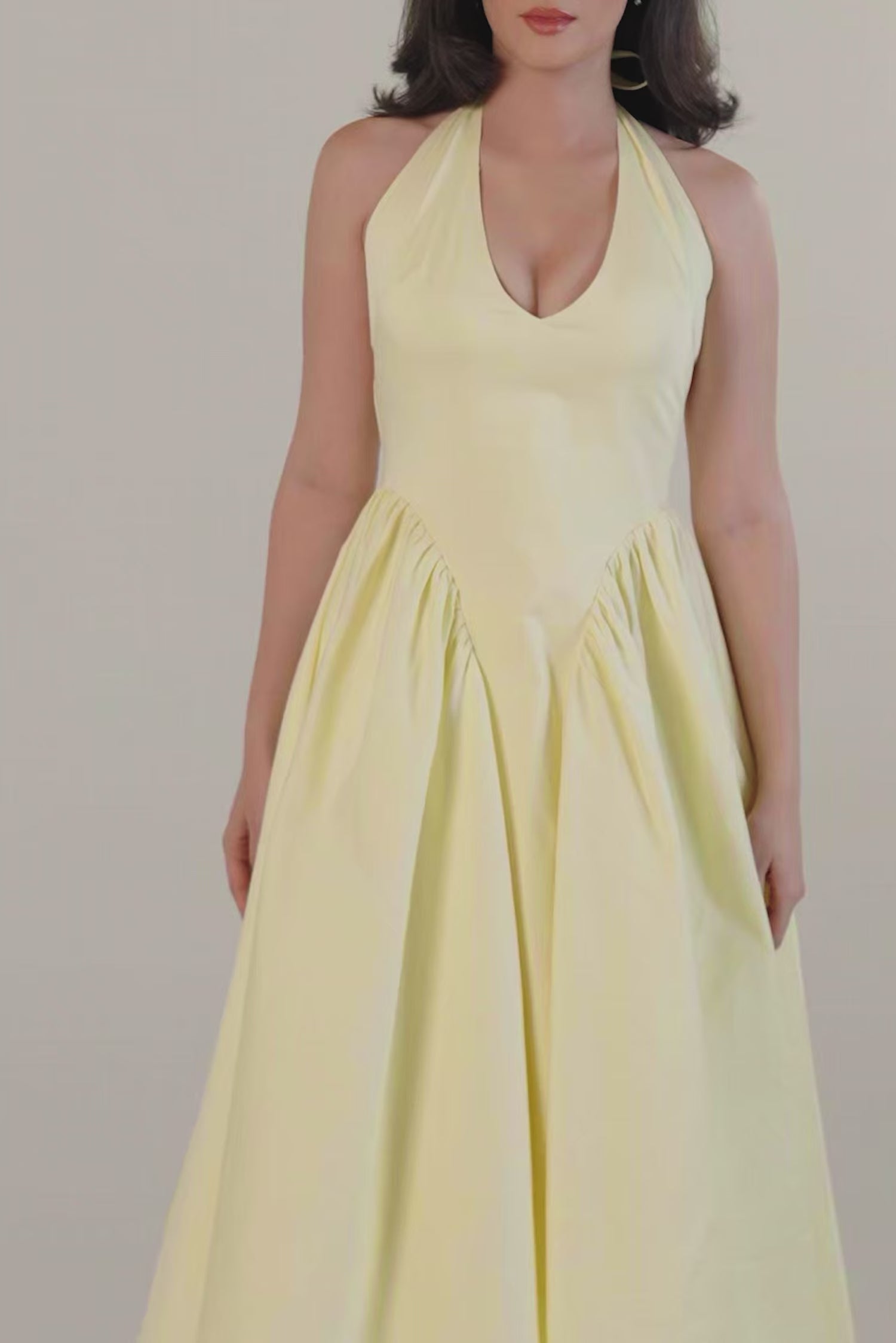 Elegant yellow halter neck midi dress front view with flared skirt and pockets