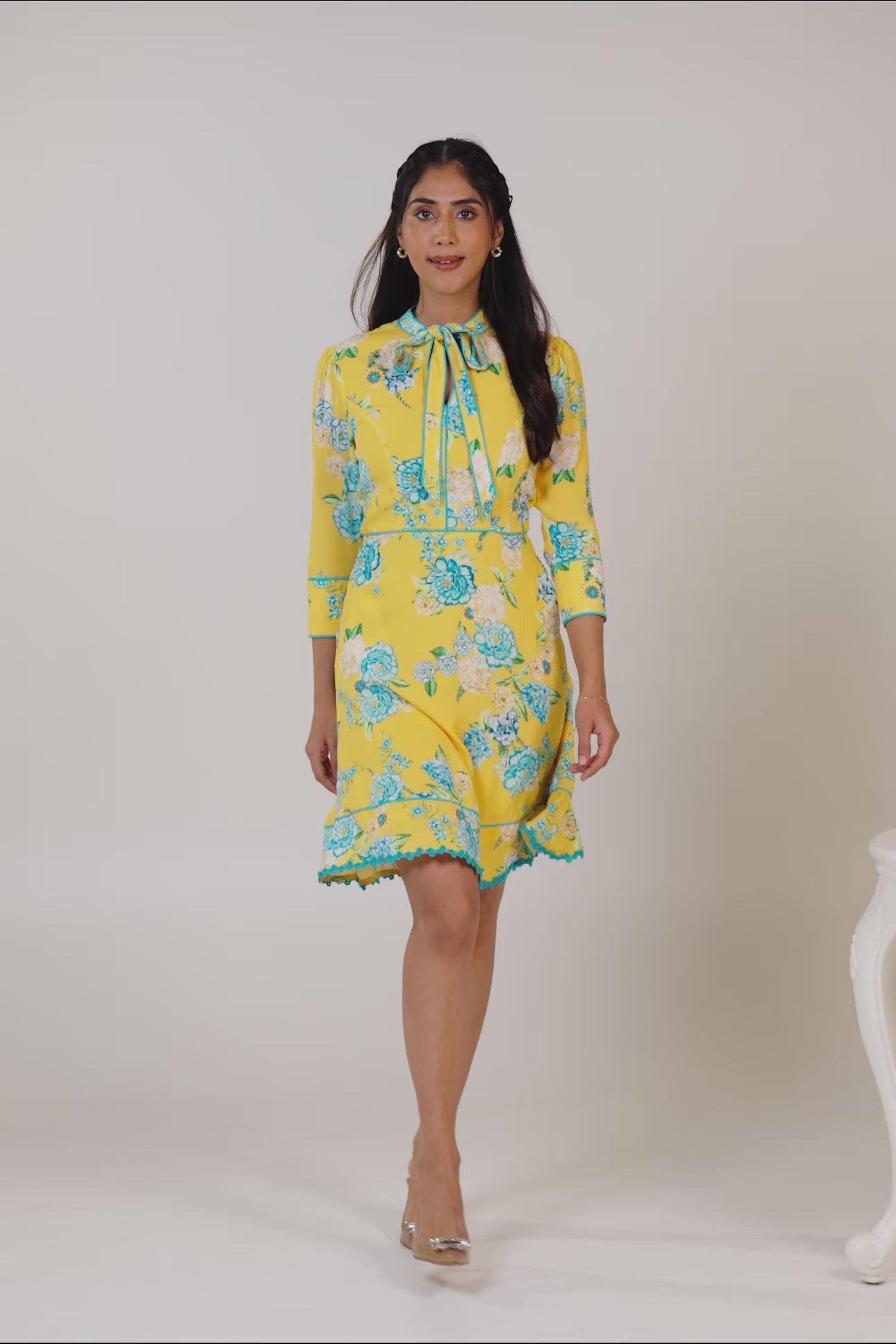 Woman in yellow floral bow tie short dress smiling