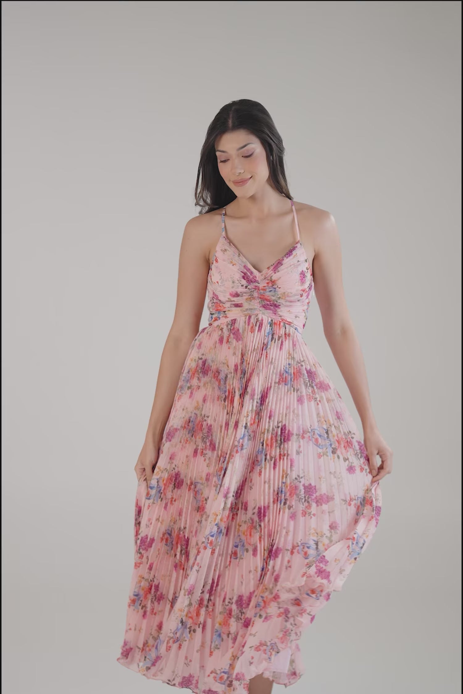 Women wearing pink floral pleated maxi dress with v-neckline and flowy skir
