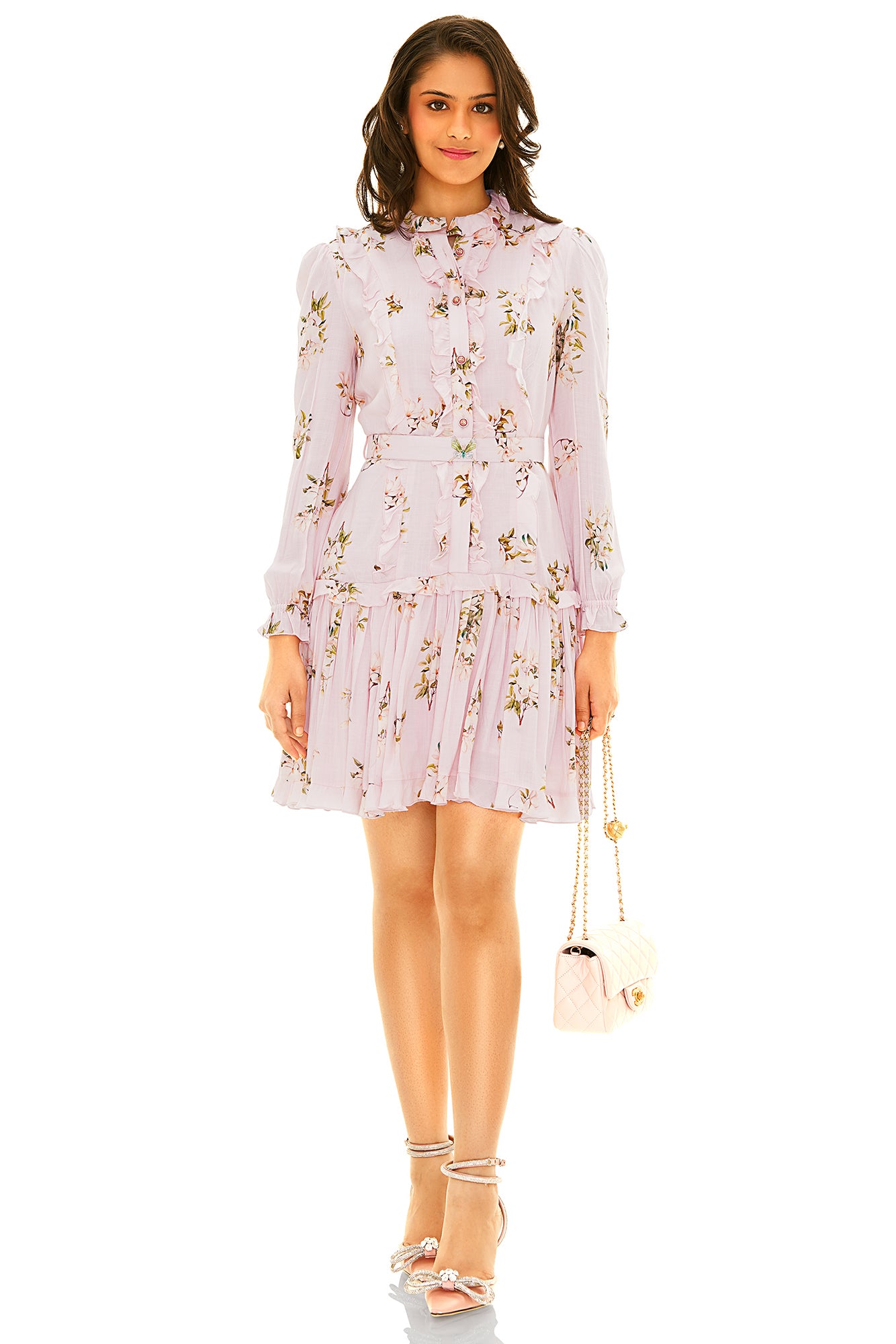 Blush floral long sleeve ruffle mini dress with belt and pleated hem, styled with strappy heels and quilted bag