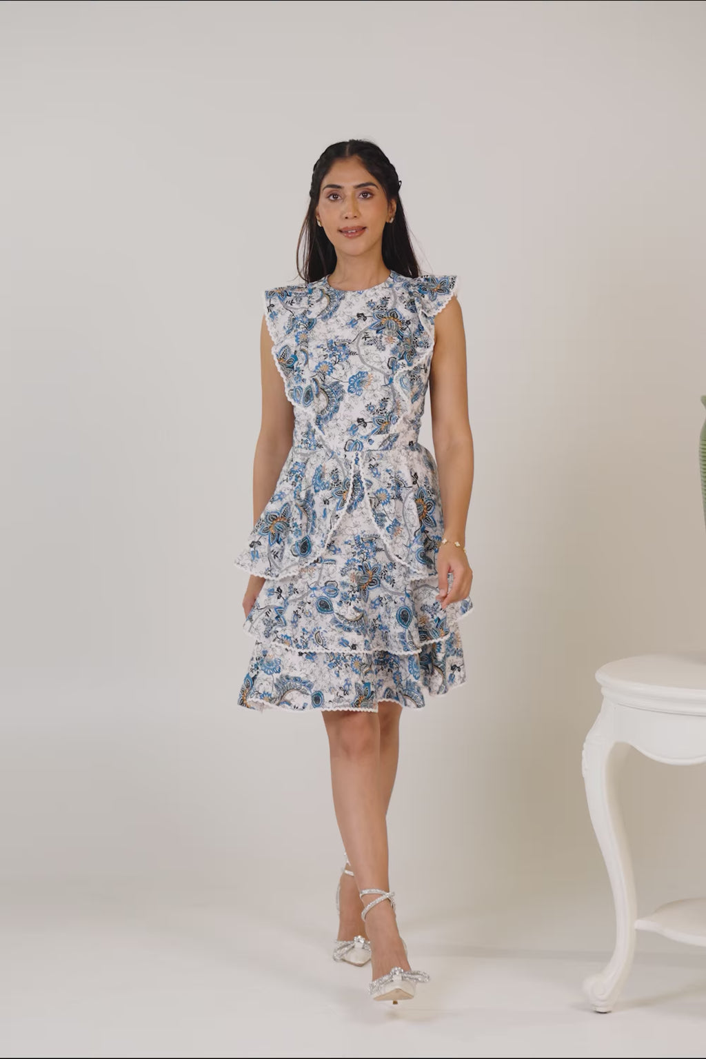 Woman smiling in blue floral ruffle midi dress with elegant heels