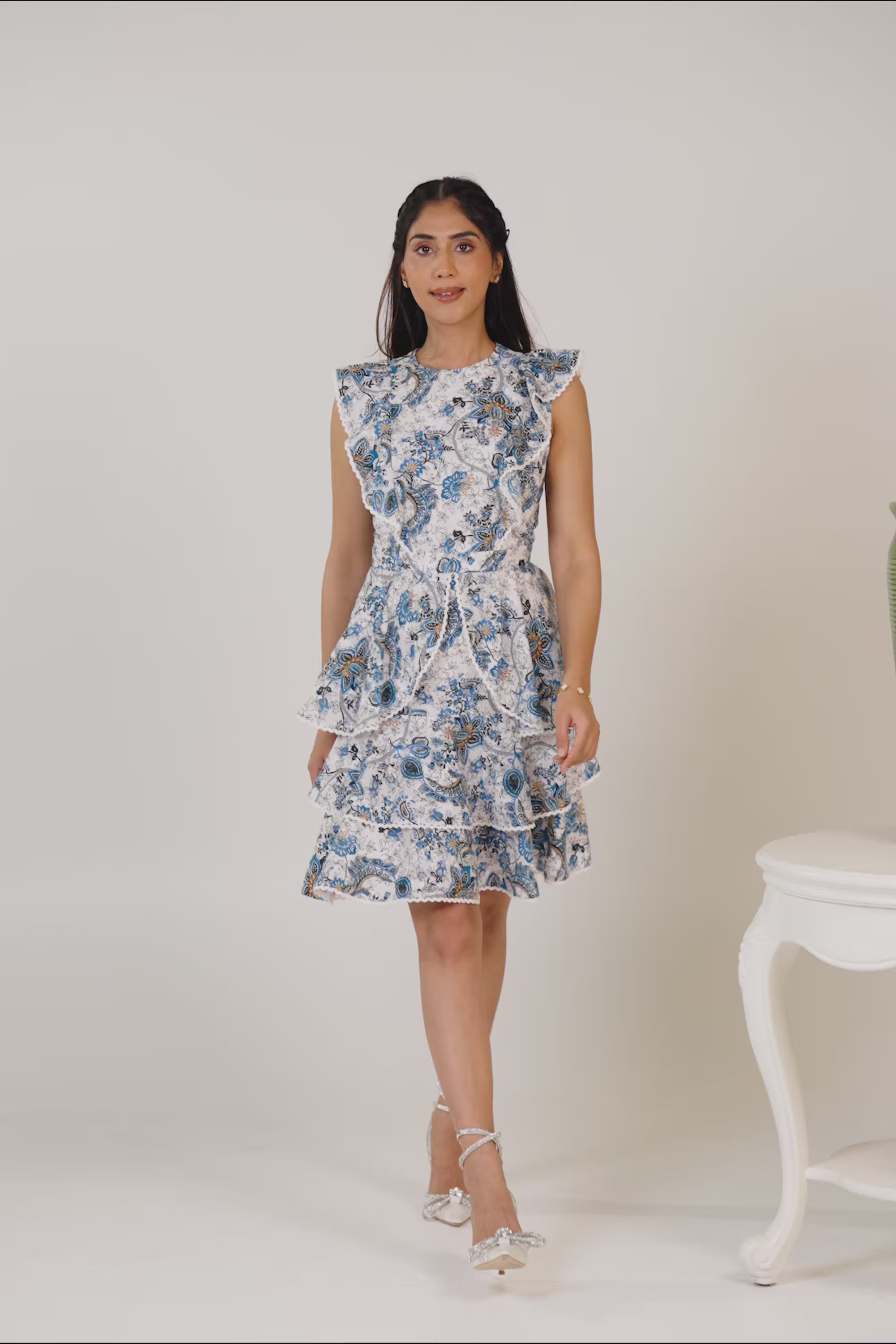 Woman smiling in blue floral ruffle midi dress with elegant heels