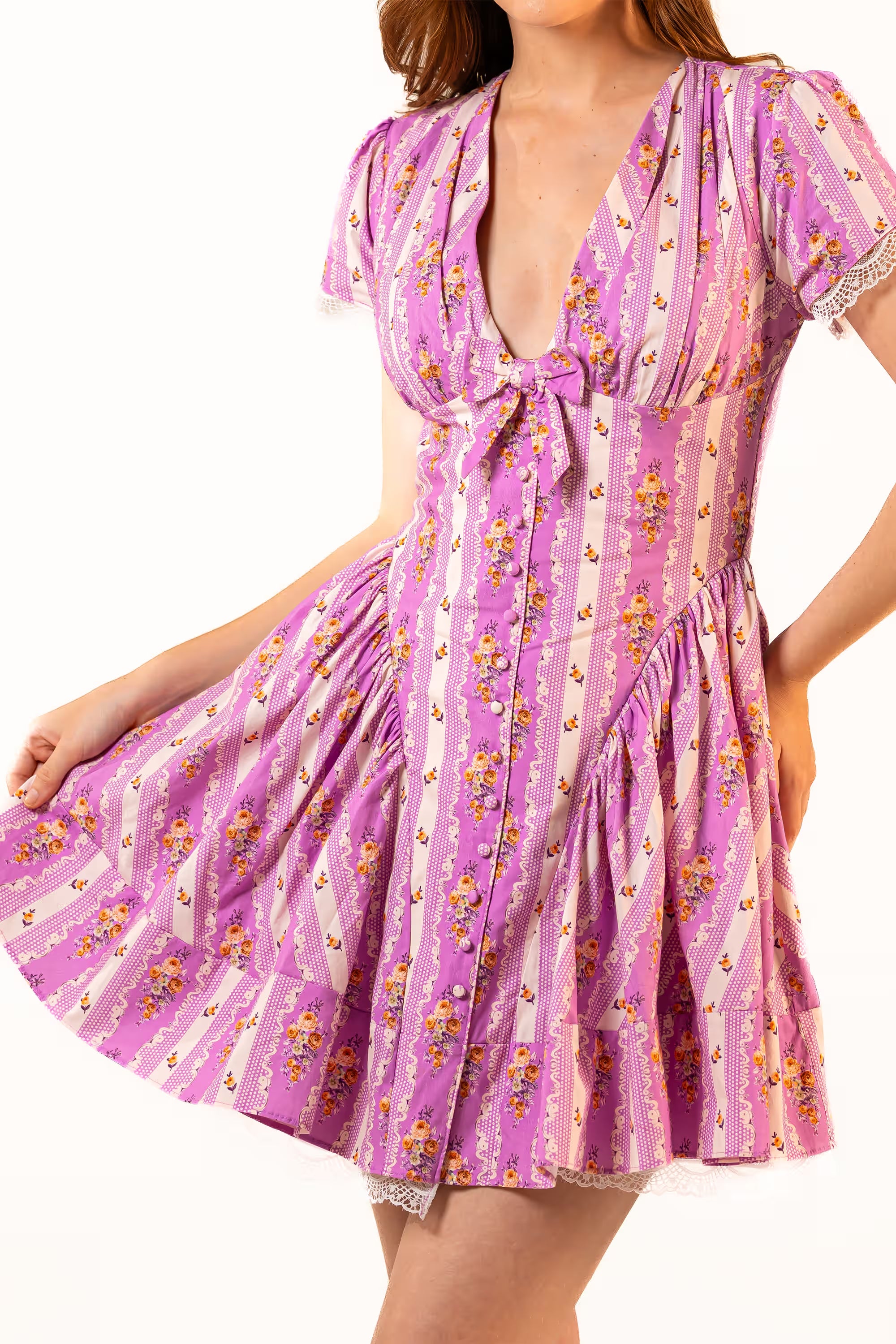 Purple floral mini dress with short puff sleeves, deep V-neckline, and flared skirt, styled with lace trim.