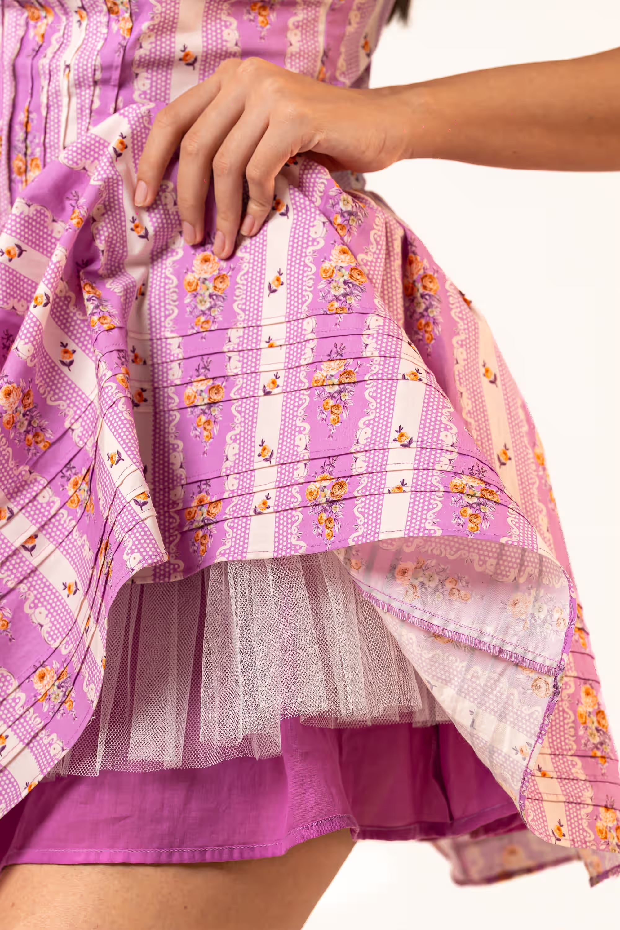 Detail of layered underskirt and net lining under purple floral mini dress.