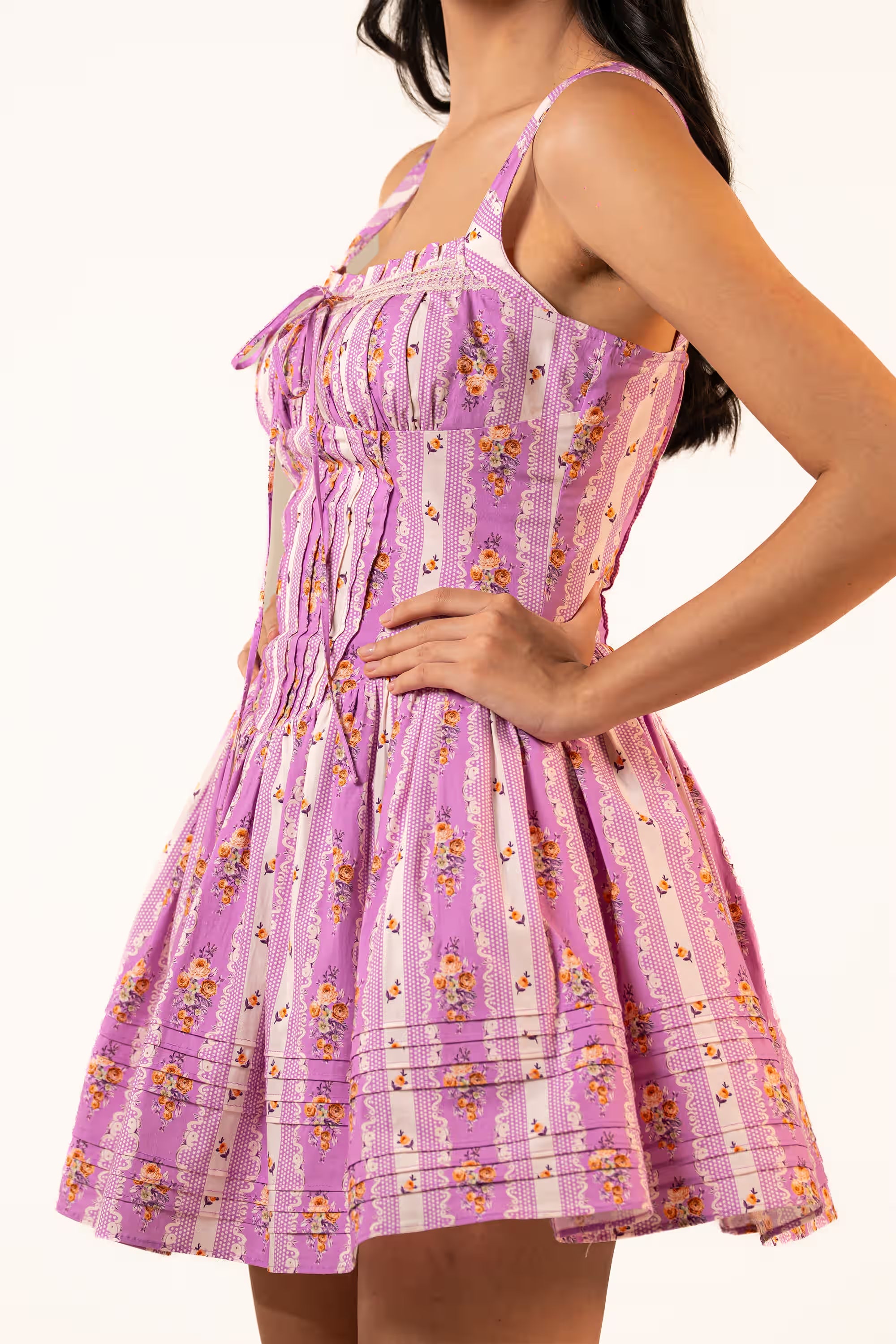 Side profile view of woman in purple floral mini dress with structured bodice and full skirt.